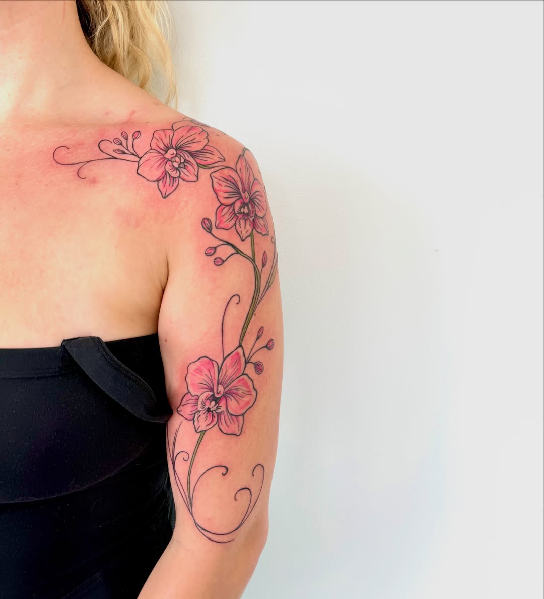 Orchids fine line tattoo on the upper arm by Lindsay Shriver