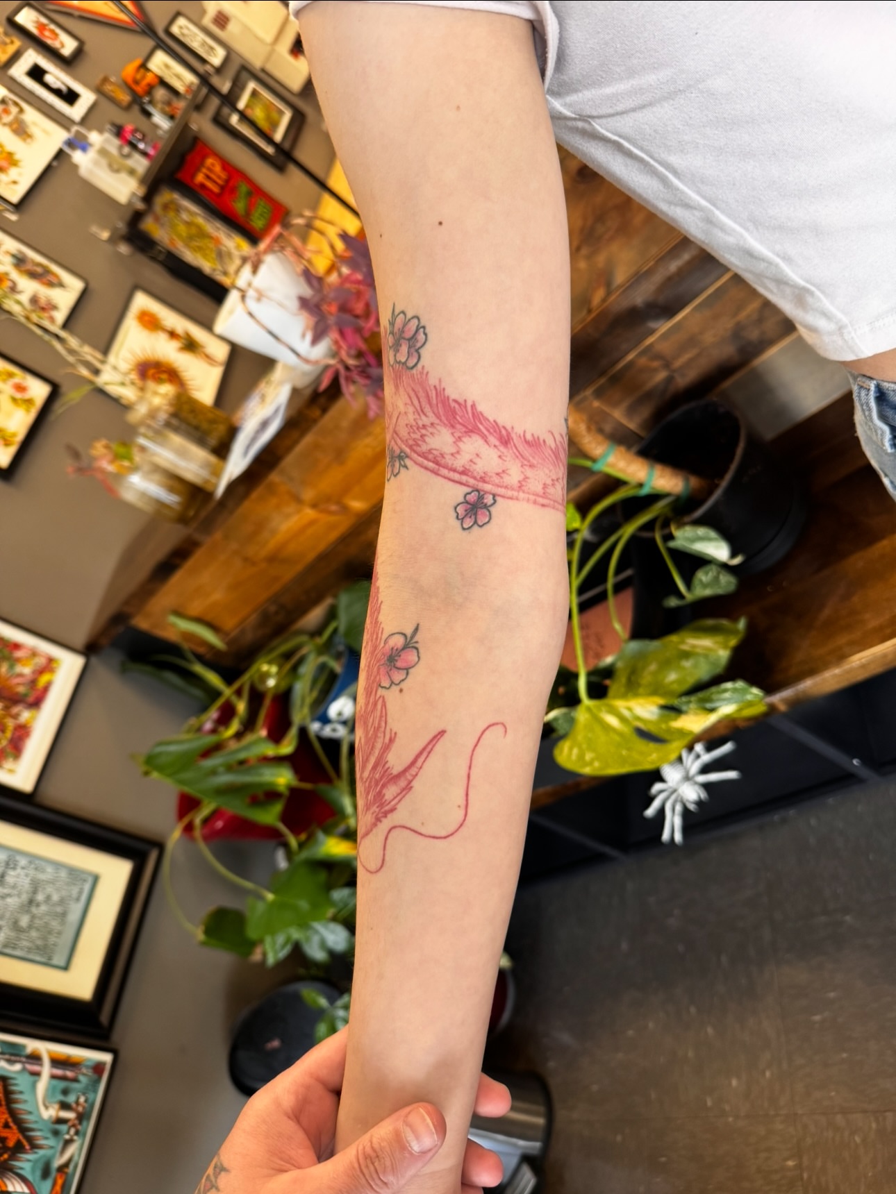 Feather and flowers American traditional tattoo on the forearm by Brad Snow