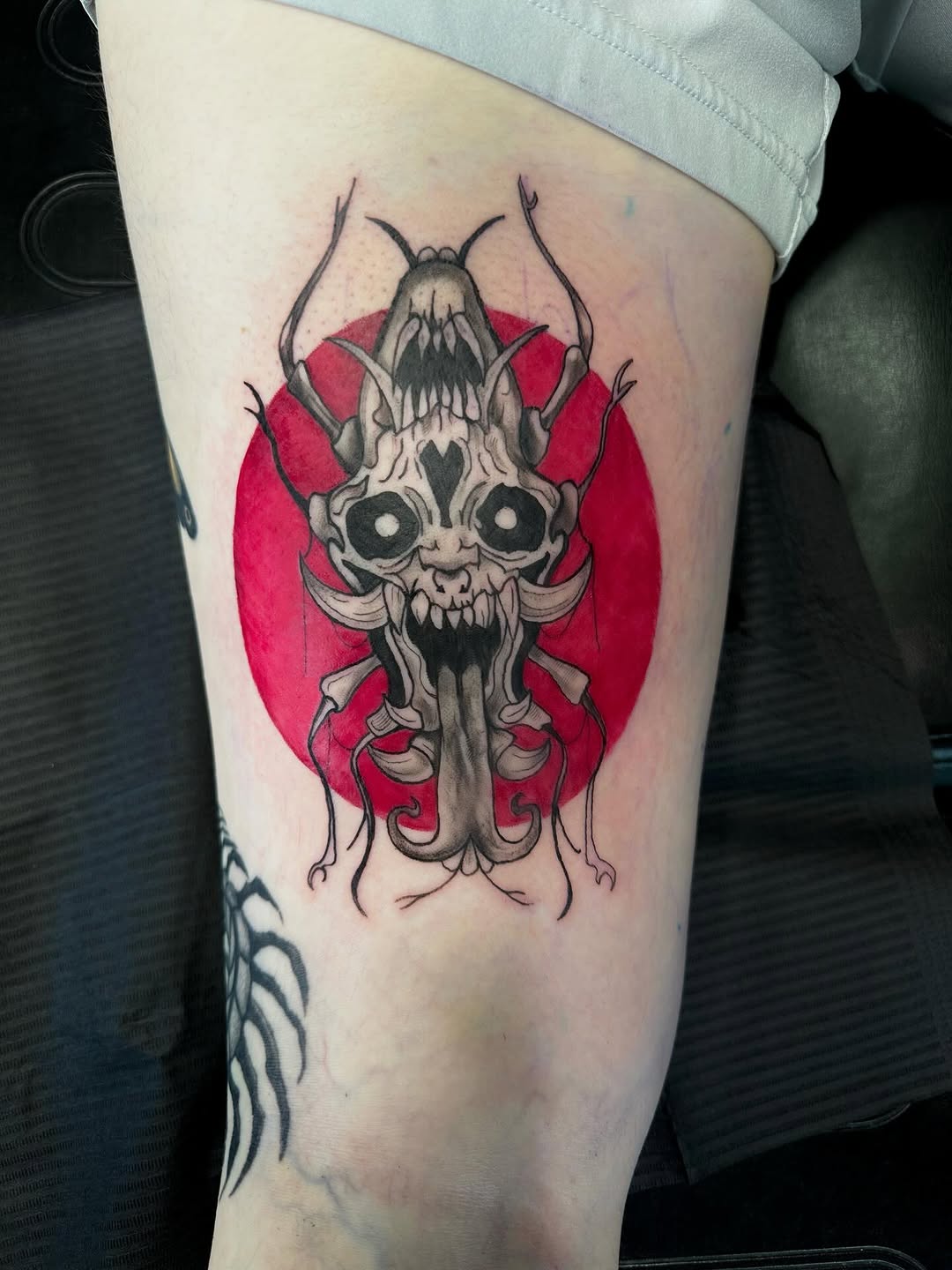 Creature skull with red circle realism tattoo on the thigh by Mika'la Berry