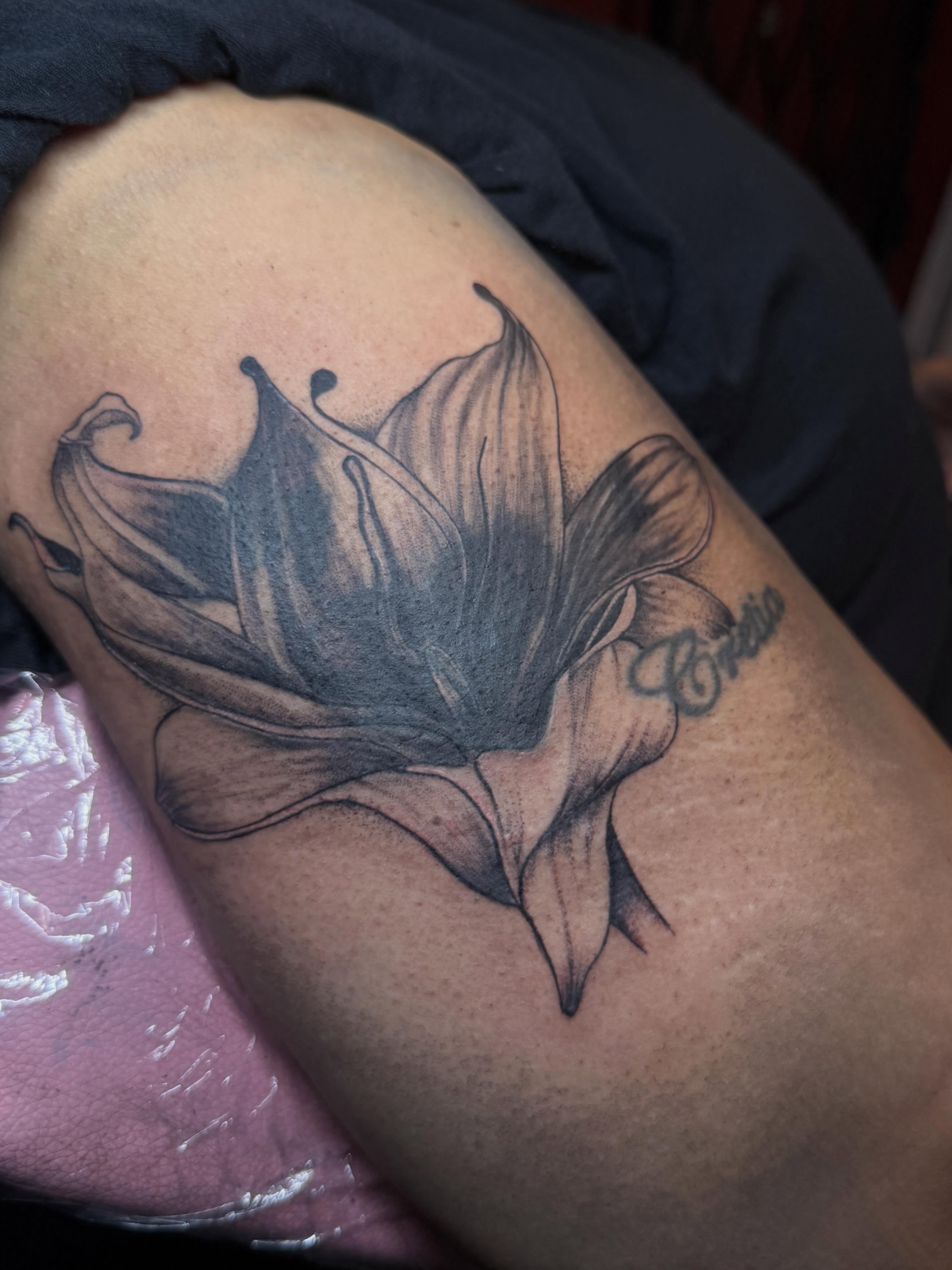 Lily black and grey tattoo on the upper arm by Destini