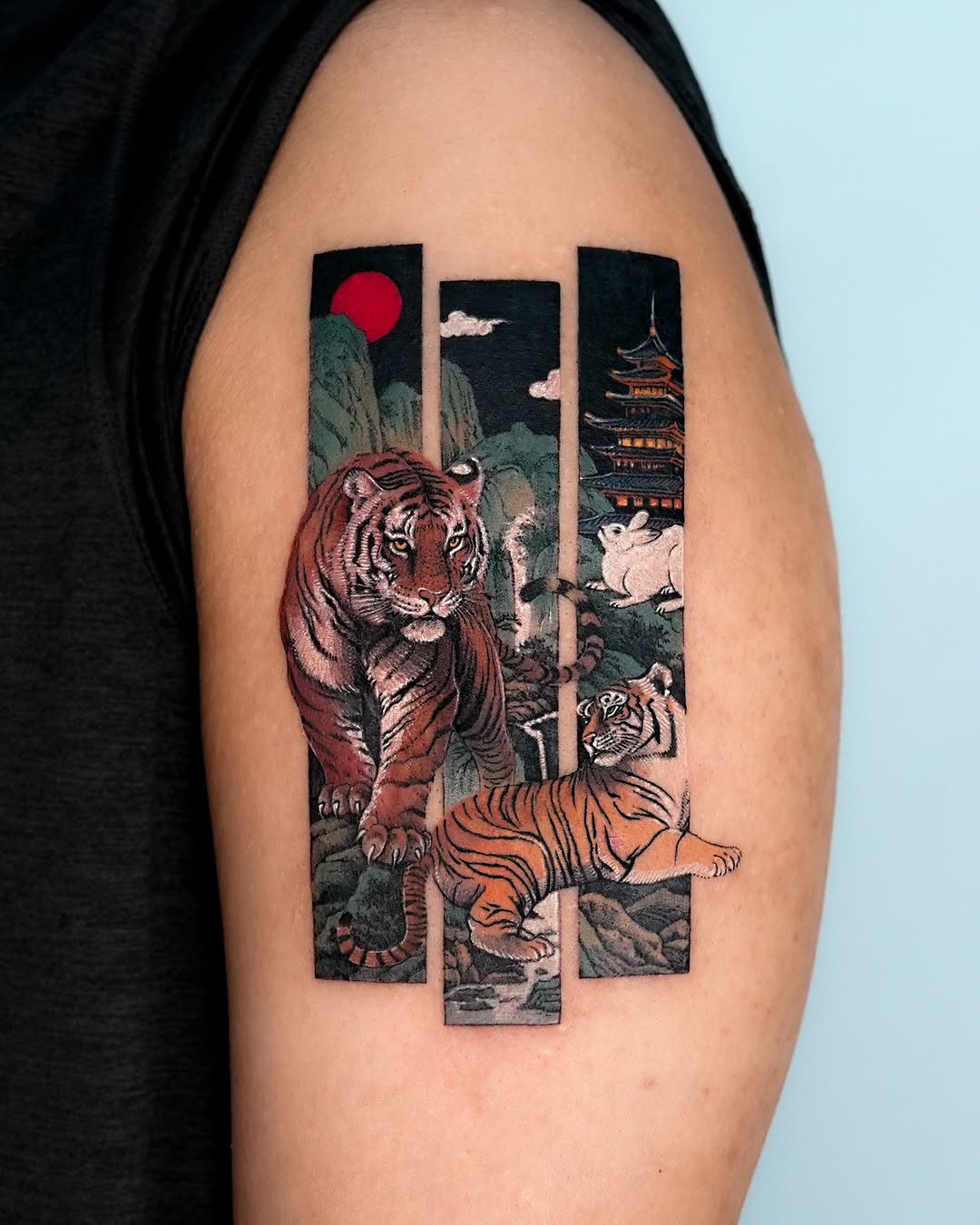 Tigers and pagoda realism tattoo on the upper arm by EQ