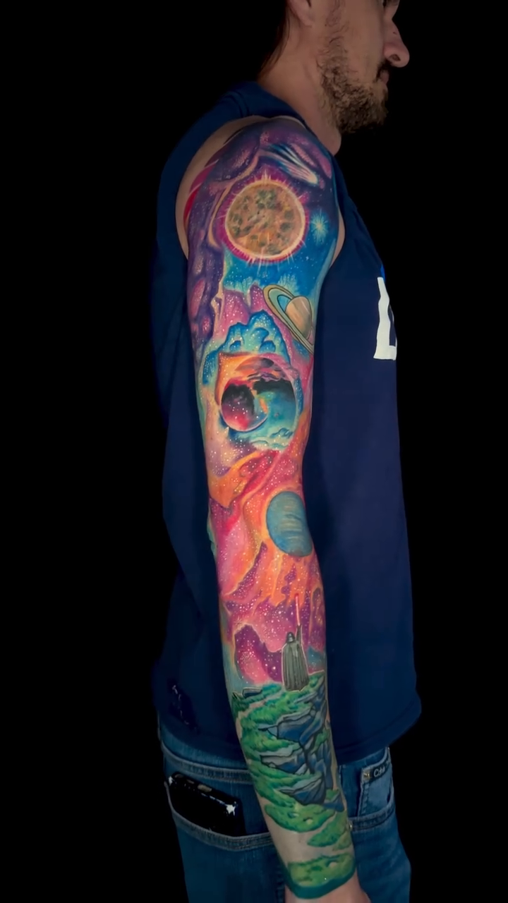 Cosmic skull and floral sleeve surrealism tattoo on the upper arm by Goga