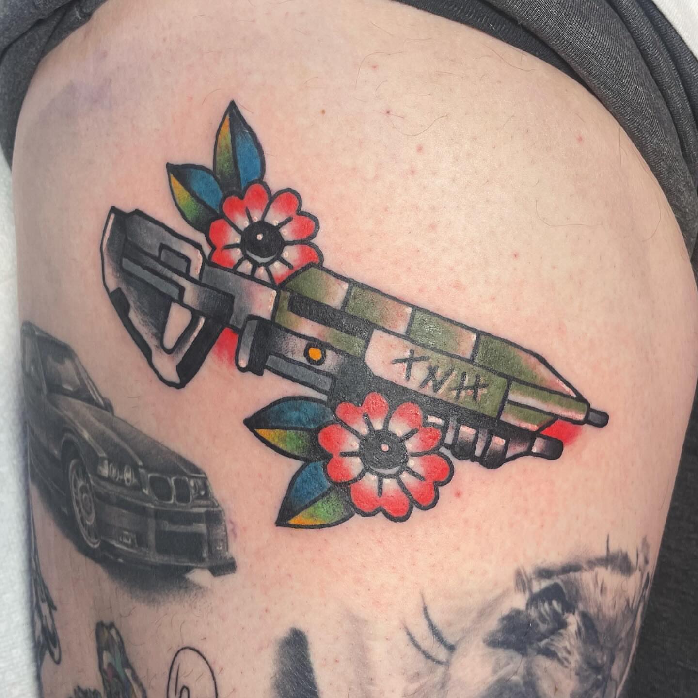 Gun and flowers American traditional tattoo on the shoulder by Robert Morrow