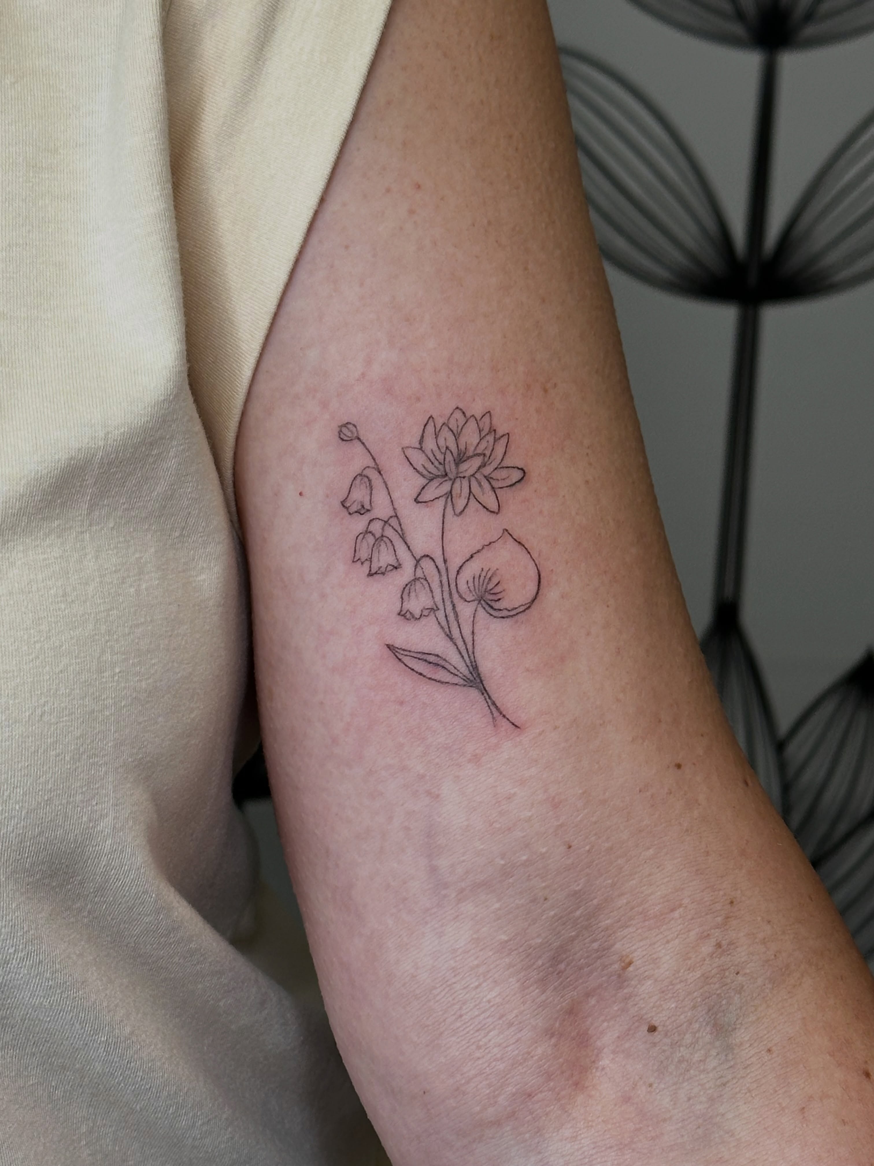 Lily of the valley and lotus fine line tattoo on the forearm by Liz