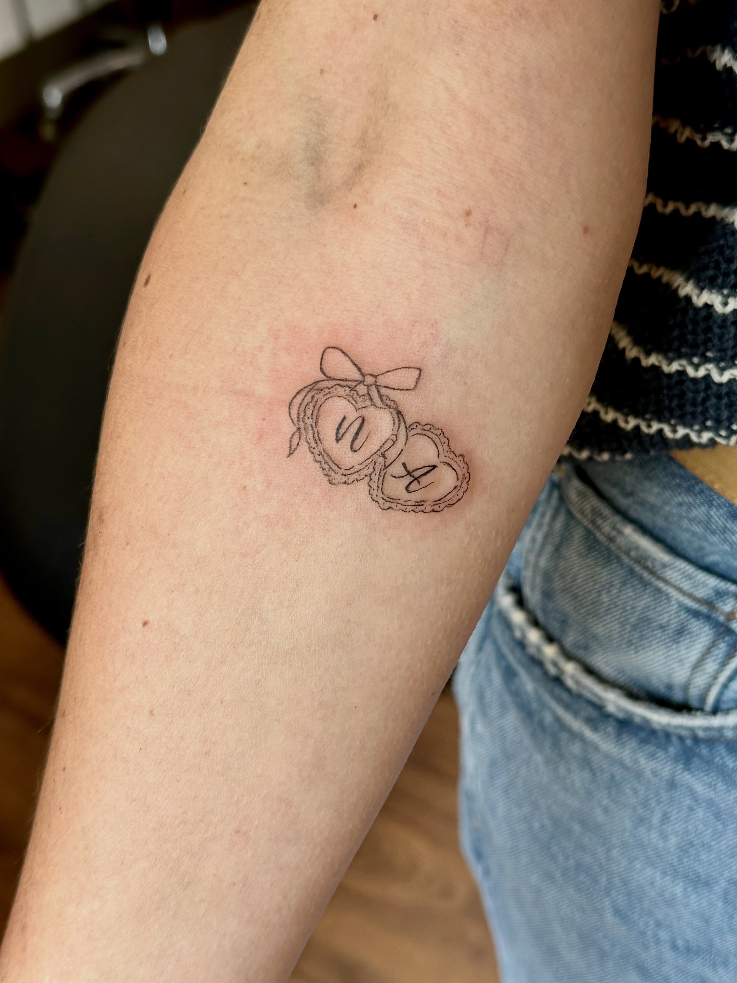 Two hearts fine line tattoo on the forearm by Liz