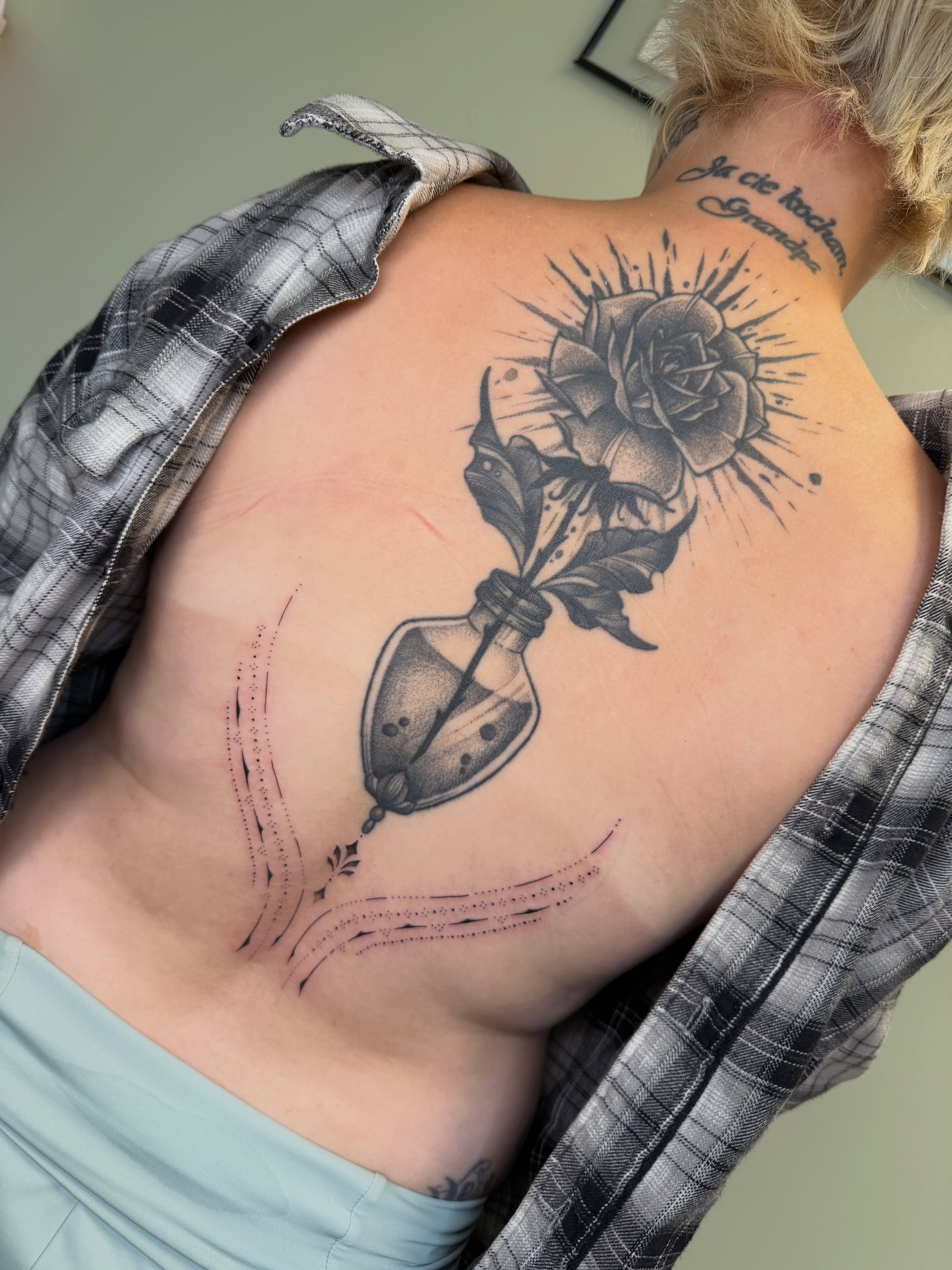 Rose in bottle black and grey tattoo on the back by Koryn Donnelly