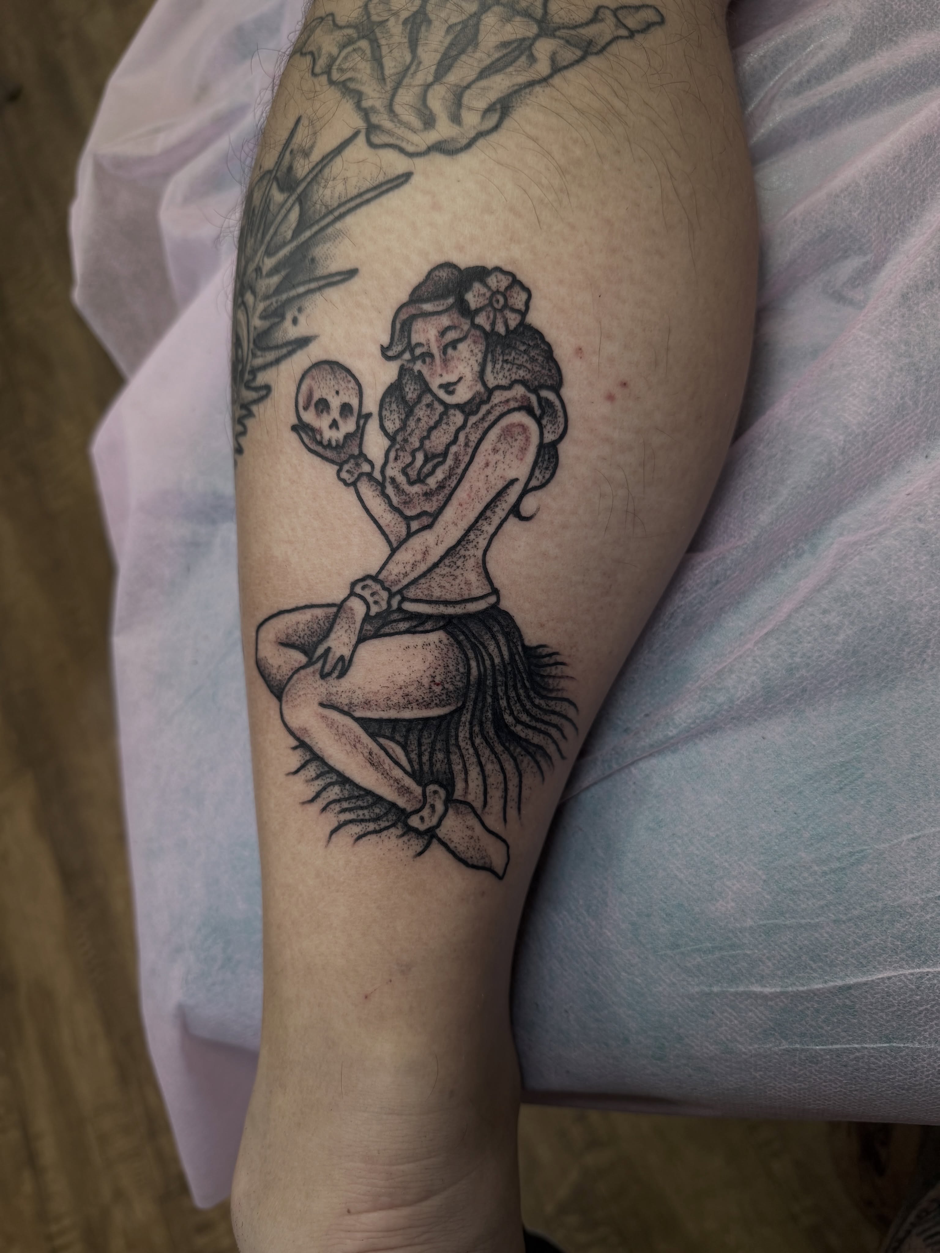 Hula dancer with skull dotwork tattoo on the forearm by Ramón Silva