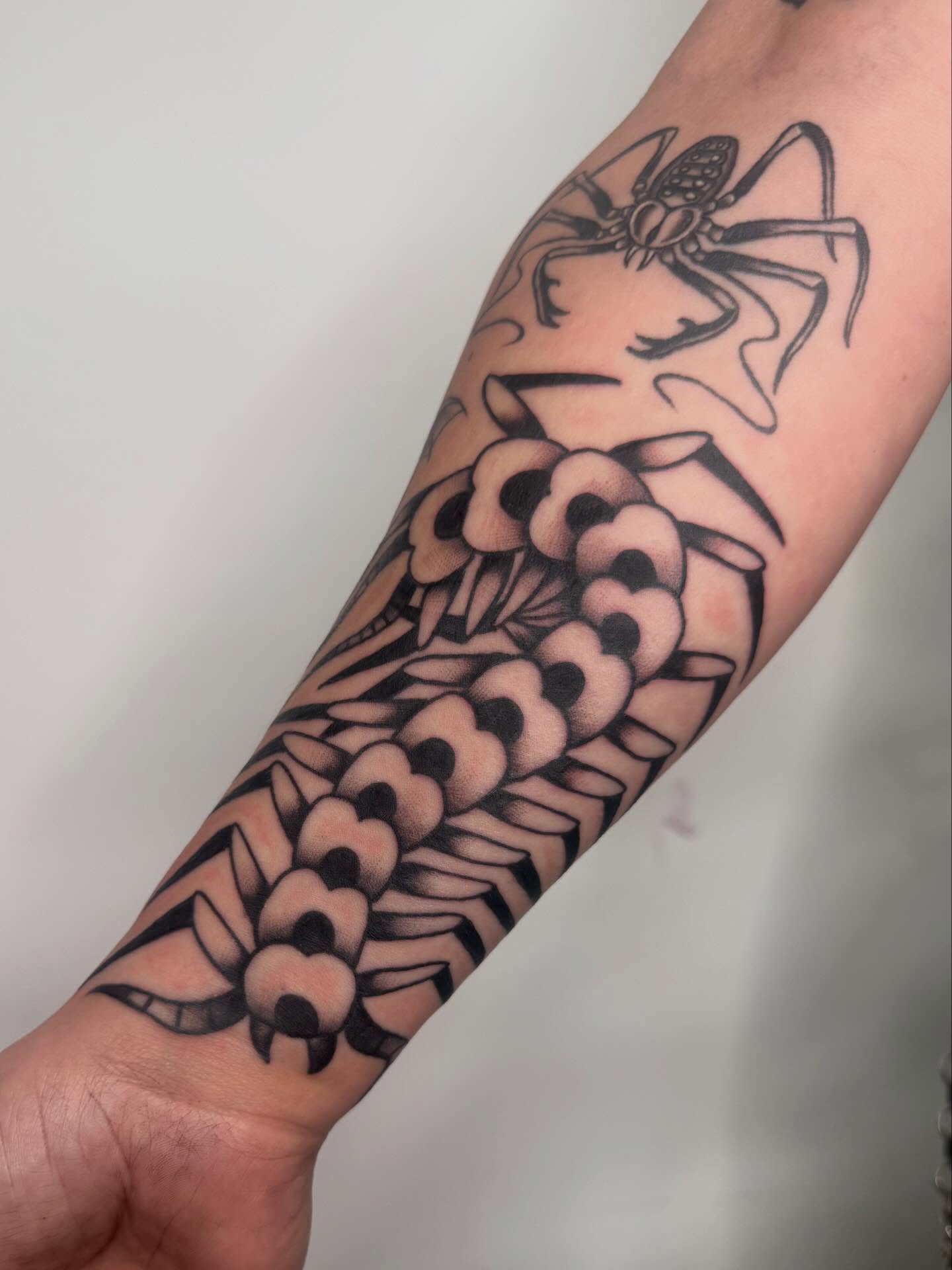 Spider and flowers black and grey tattoo on the forearm by Jacqui Rose
