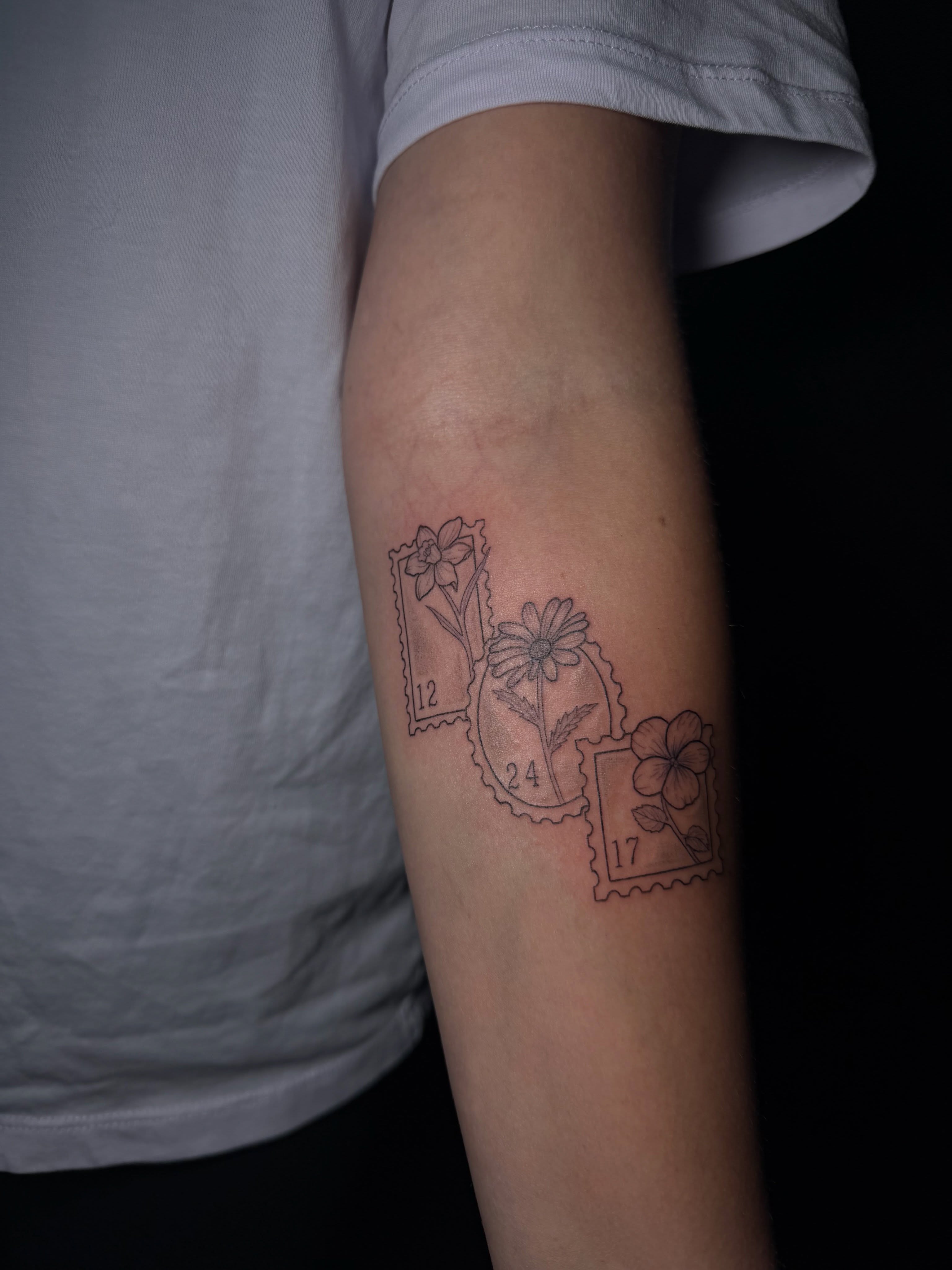 Flowers and postage stamps black and grey tattoo on the forearm by Ink Darling, Carlisle, Iowa