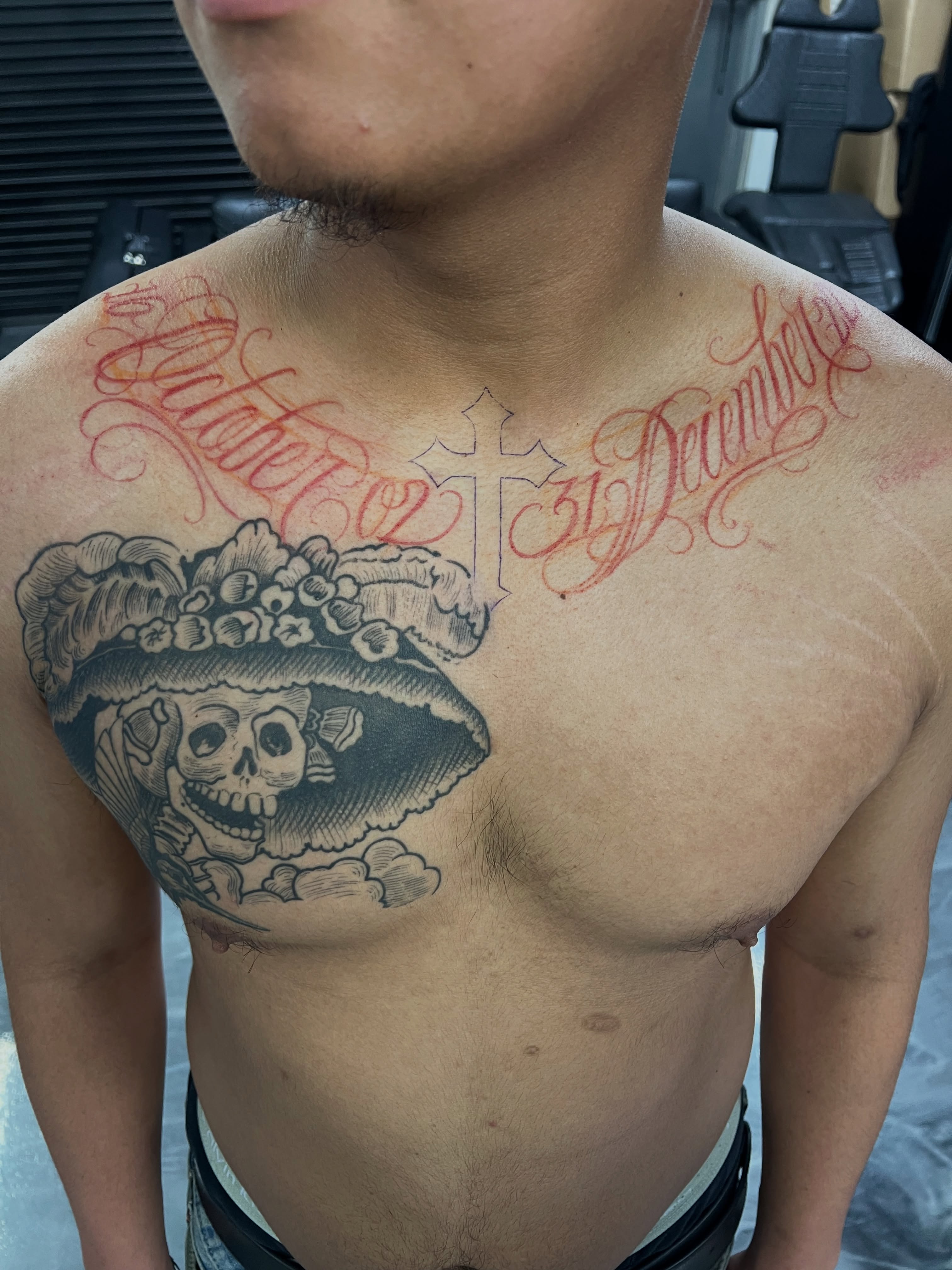 Skull wearing floral headdress black and grey tattoo on the chest by Lettering