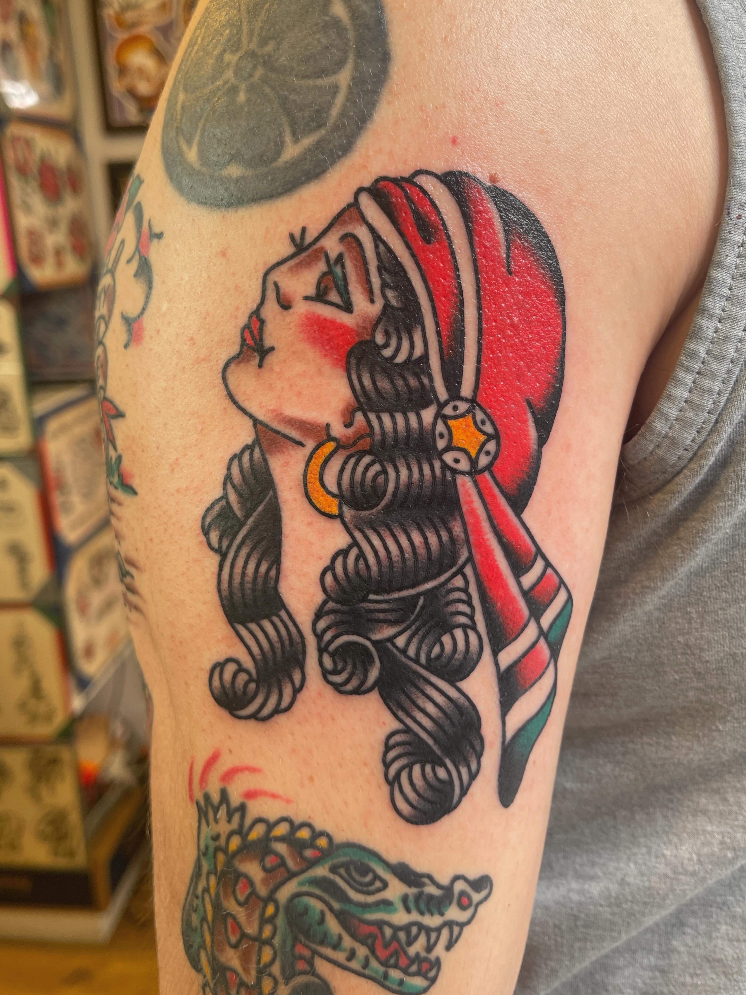 Woman with snake American traditional tattoo on the upper arm by Spencer Reisbeck