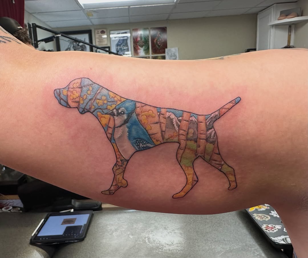 Dog with landscape and bird realism tattoo on the upper arm by Bosco Layne
