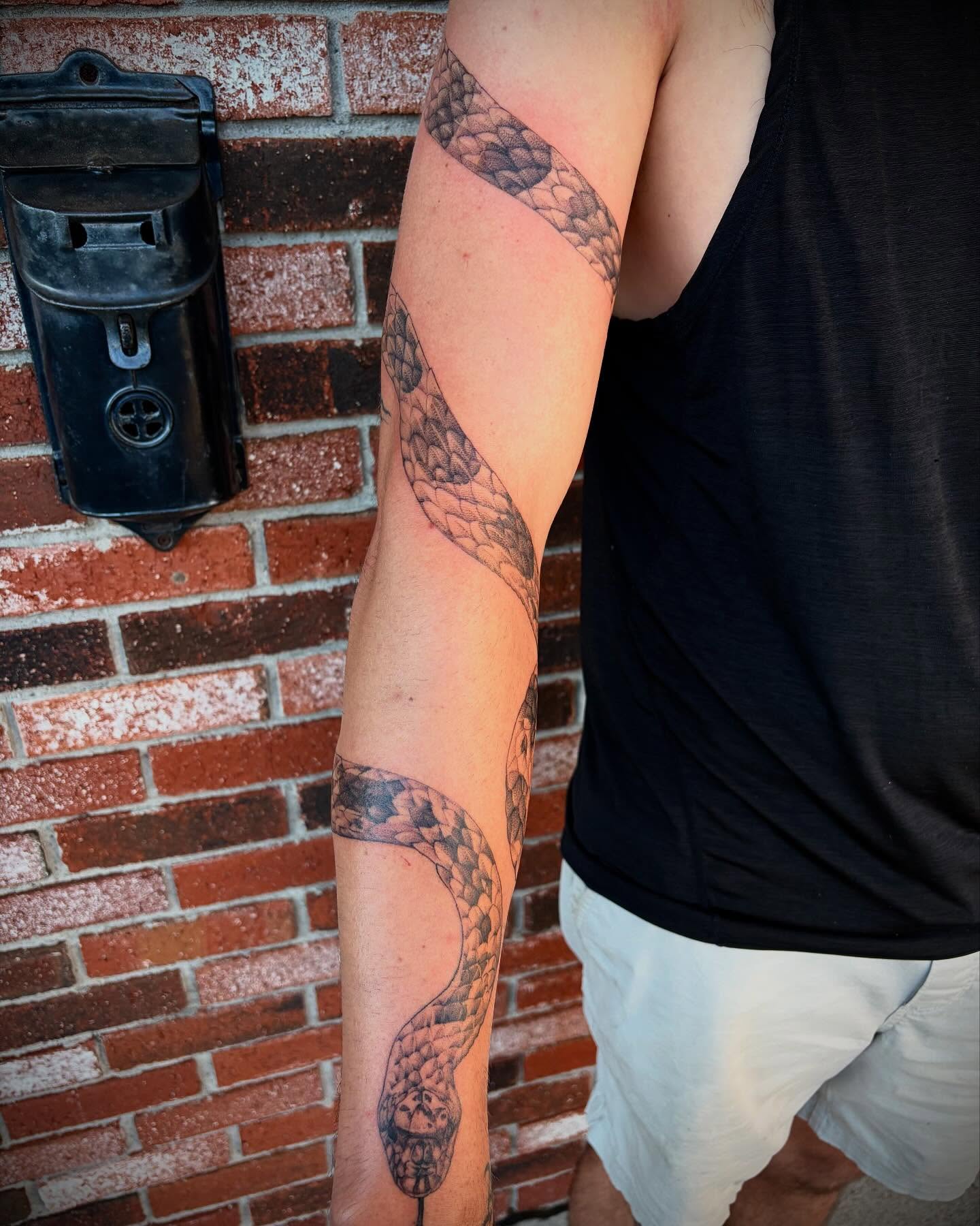 Snake black and grey tattoo on the forearm by Emily Falkowski