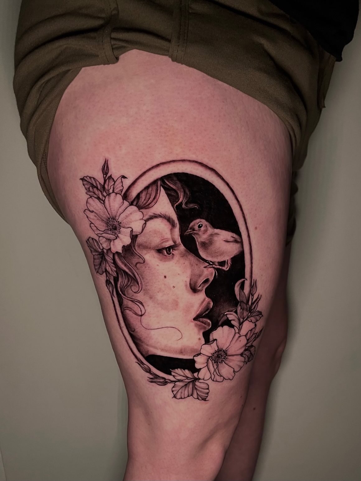 Woman's face with bird realism tattoo on the thigh by Emma Mathis, Springfield, Oregon