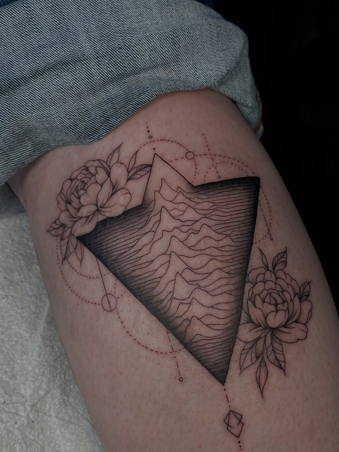 Mountain range within triangle with flowers fine line tattoo on the thigh by 𝔍𝔲𝔩𝔦𝔞, New York, New York