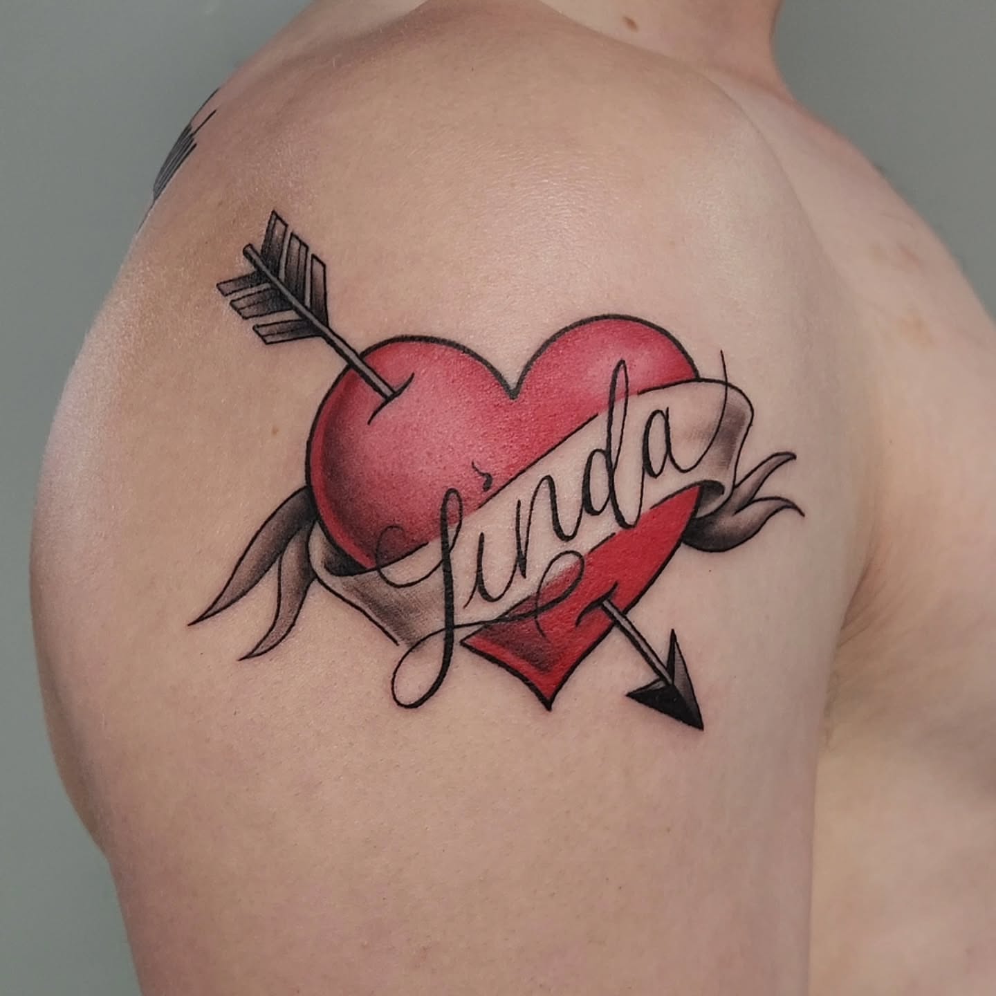 Heart with arrow American traditional tattoo on the shoulder by Jason August