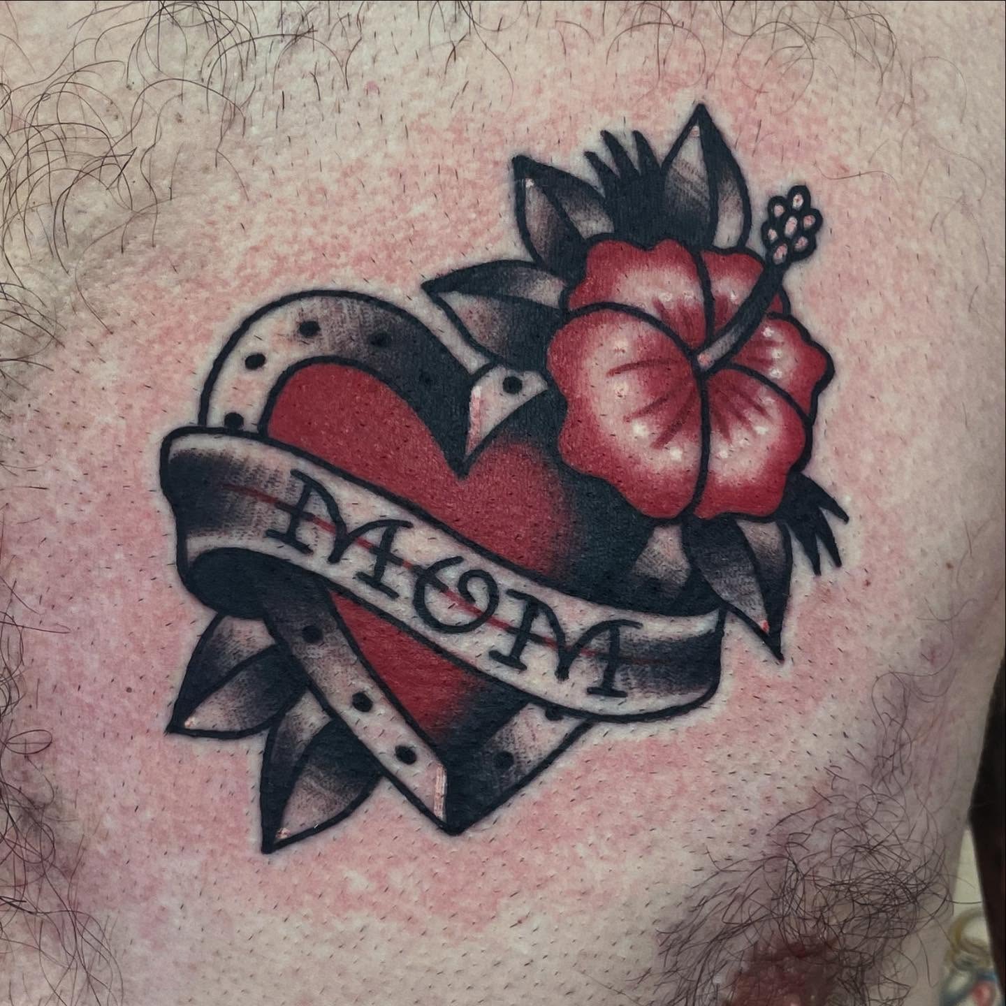 Heart with flower and ribbon American traditional tattoo on the chest by Robert Morrow
