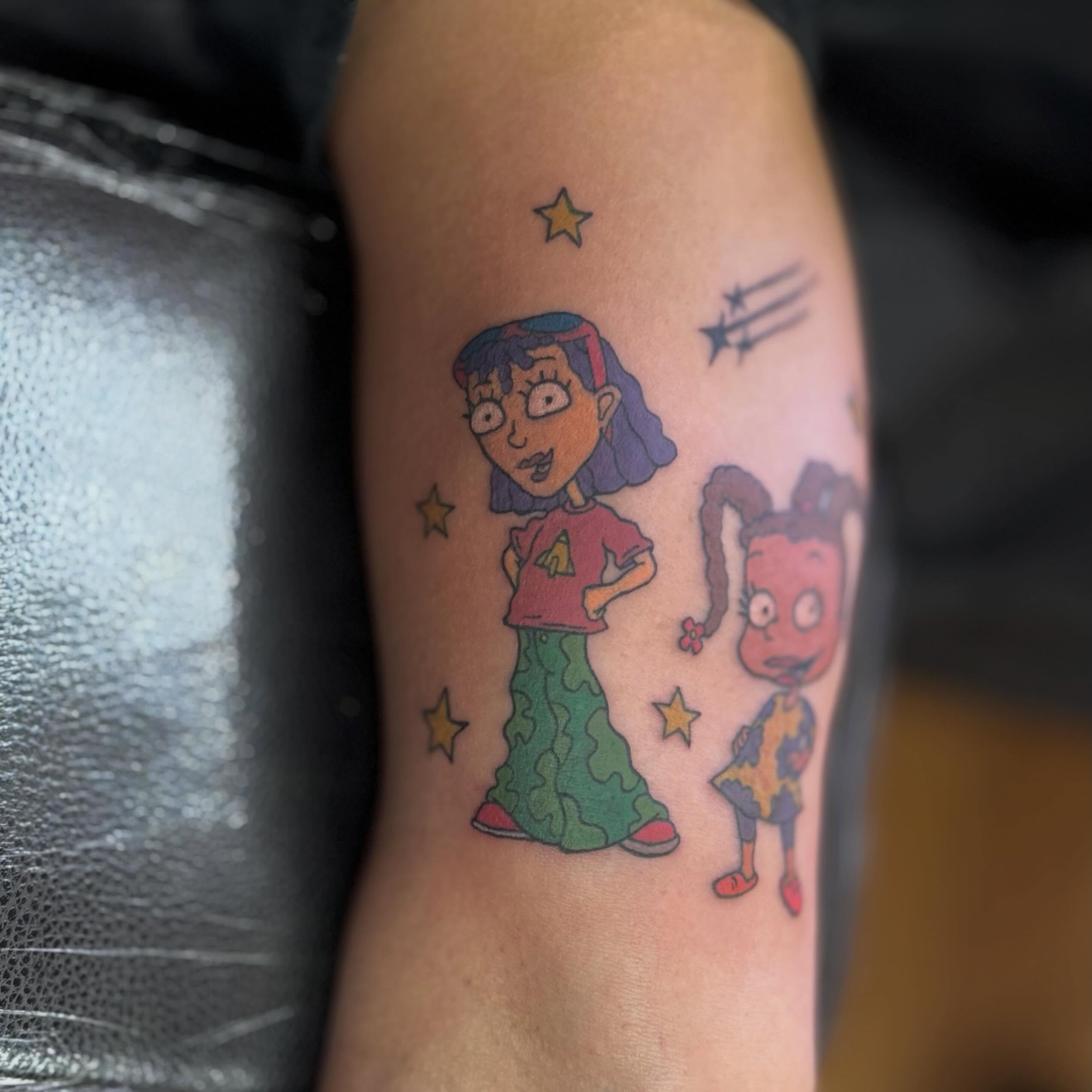 Characters from cartoon illustrative tattoo on the forearm by Nic