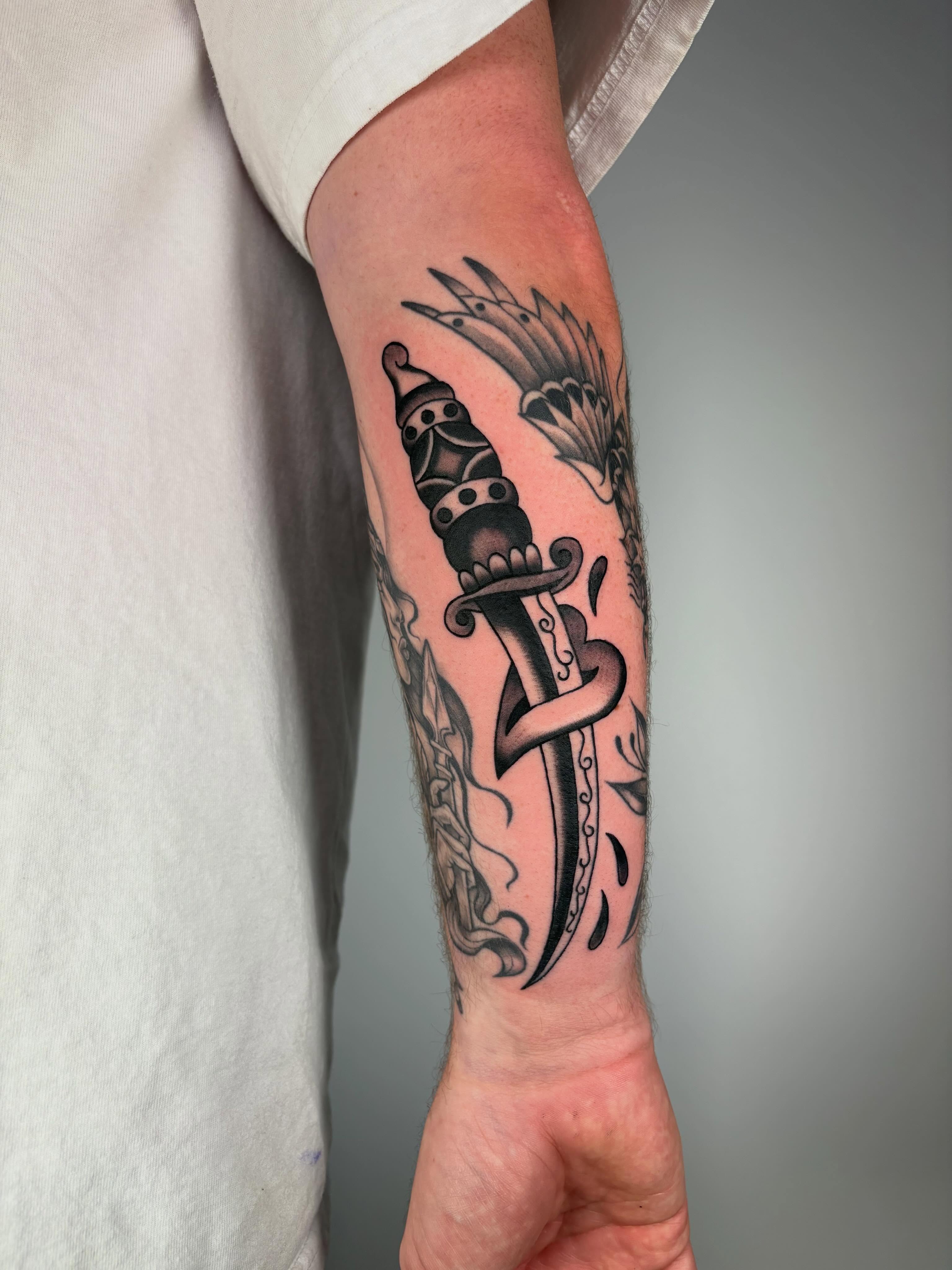 Knife and butterfly black and grey tattoo on the forearm by Lorelei