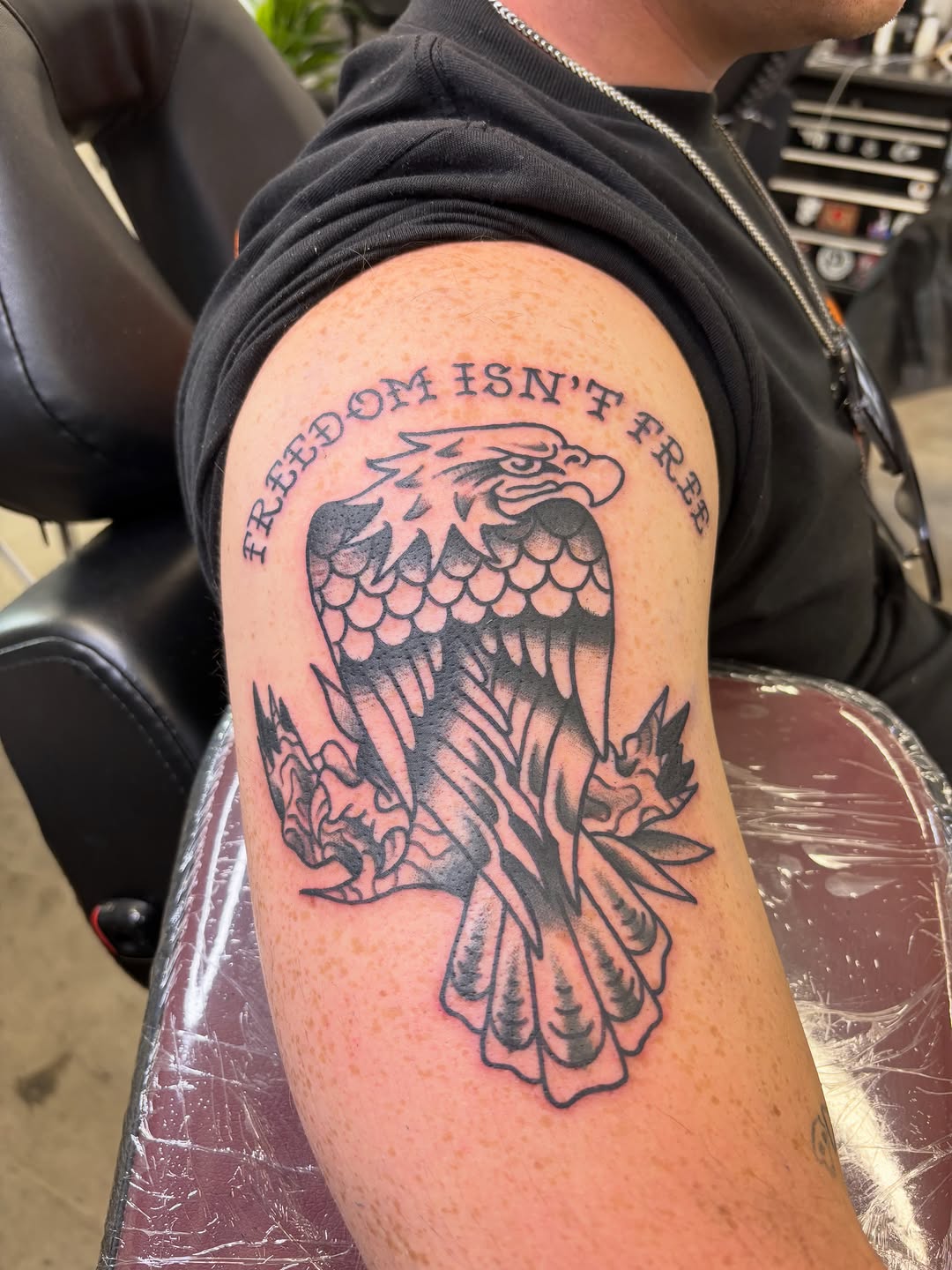 Eagle with text tattoo on the upper arm by 𝐉𝐨𝐞𝐥 𝐒𝐭𝐞𝐞𝐥𝐞