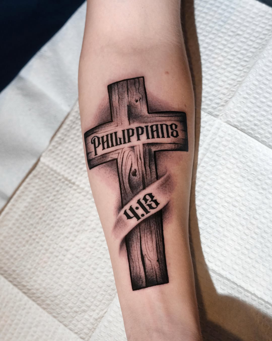 Cross with Philippians 4:13 black and grey tattoo on the forearm by Danny Pando