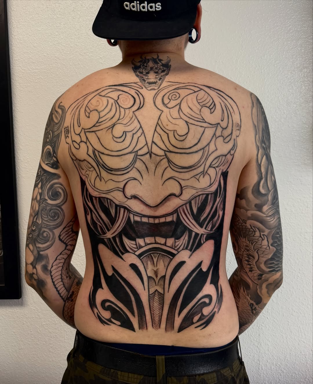 Mask black and grey tattoo on the back by Caloy Obra