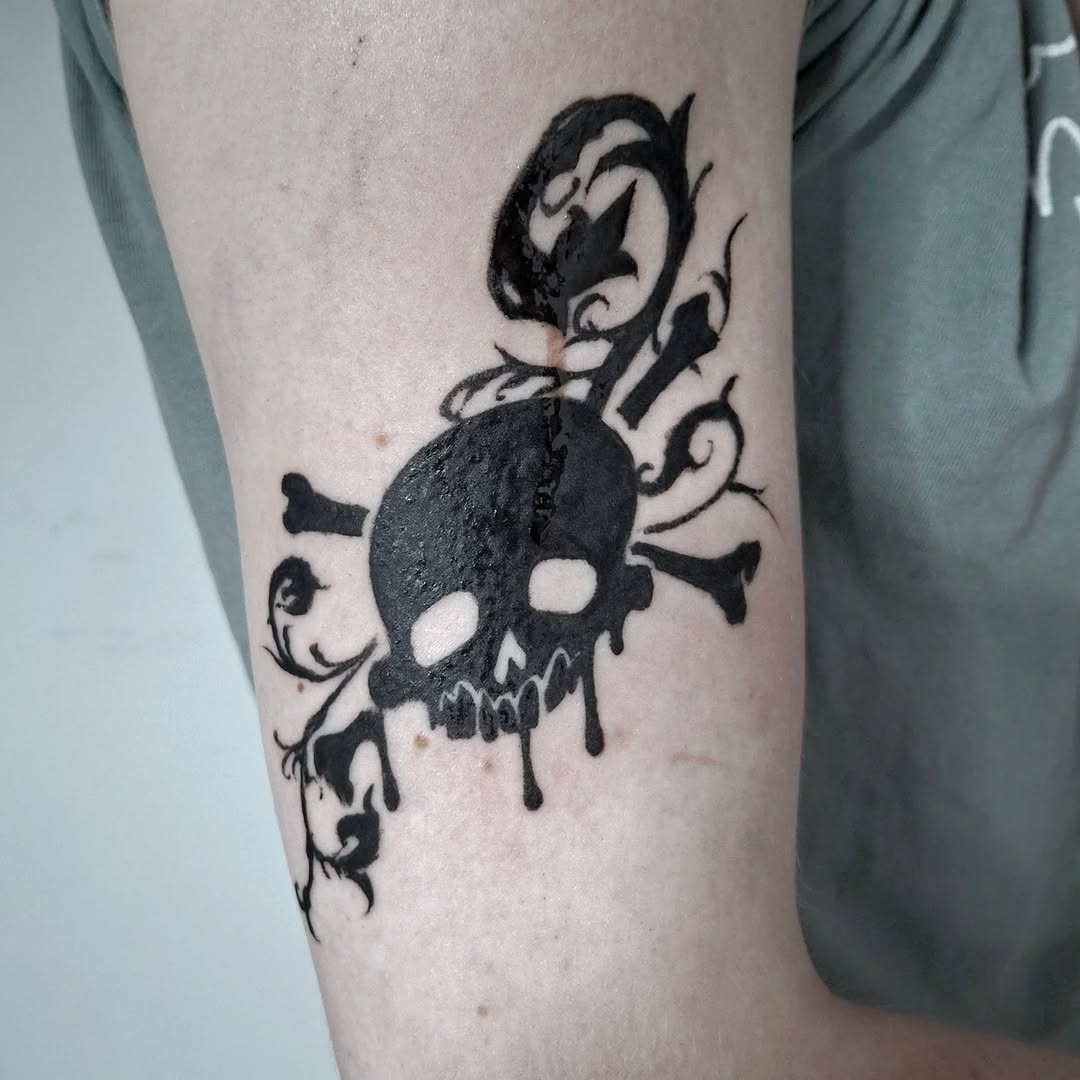 Skull and crossbones with dripping effect tattoo on the forearm by hallowed girl tattoo