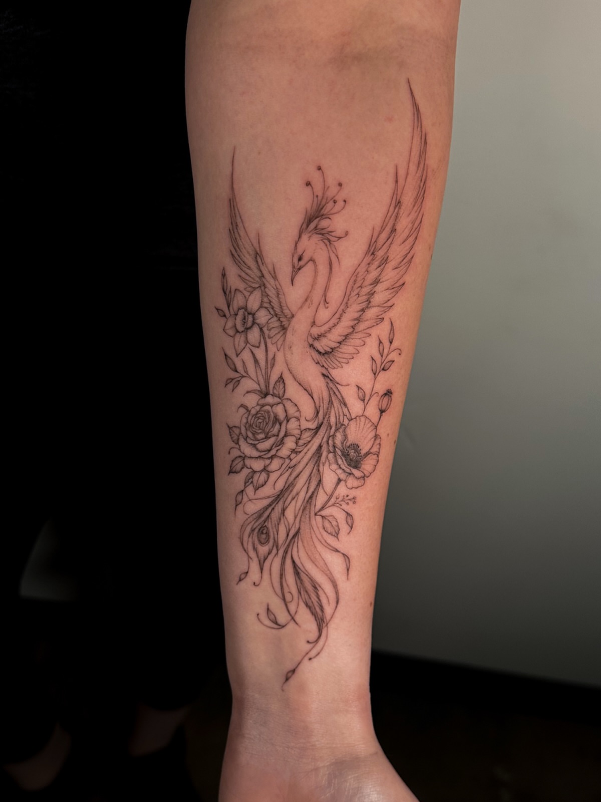 Phoenix and floral black and grey tattoo on the forearm by Caroline + Utah Tattoo Artist