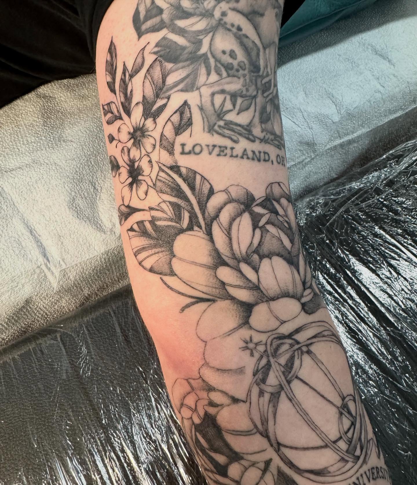 Lotus flower and floral arrangement realism tattoo on the forearm by C.J. Pennington