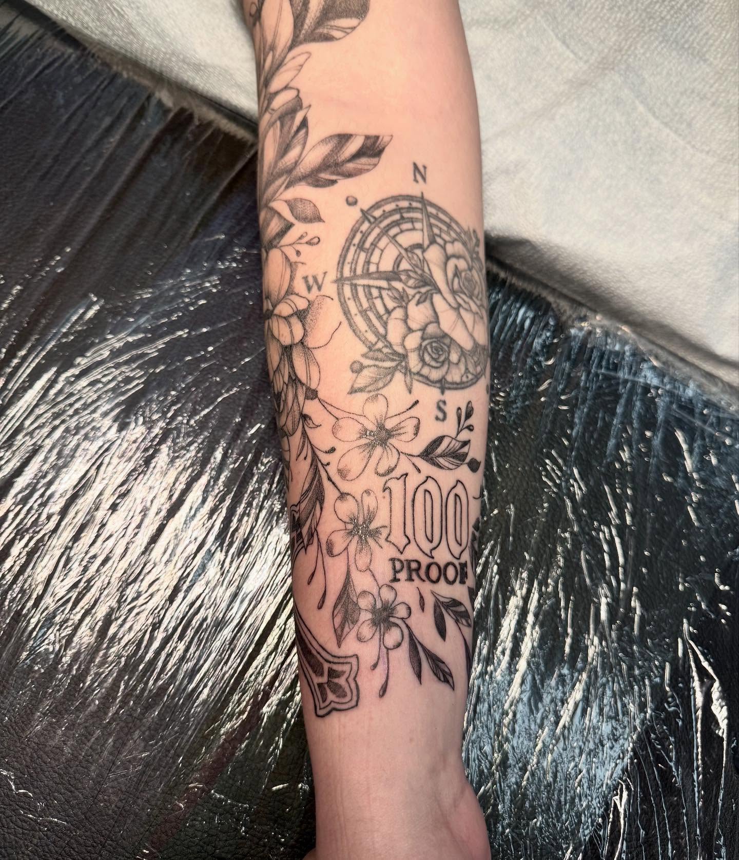 Compass and floral black and grey tattoo on the forearm by C.J. Pennington