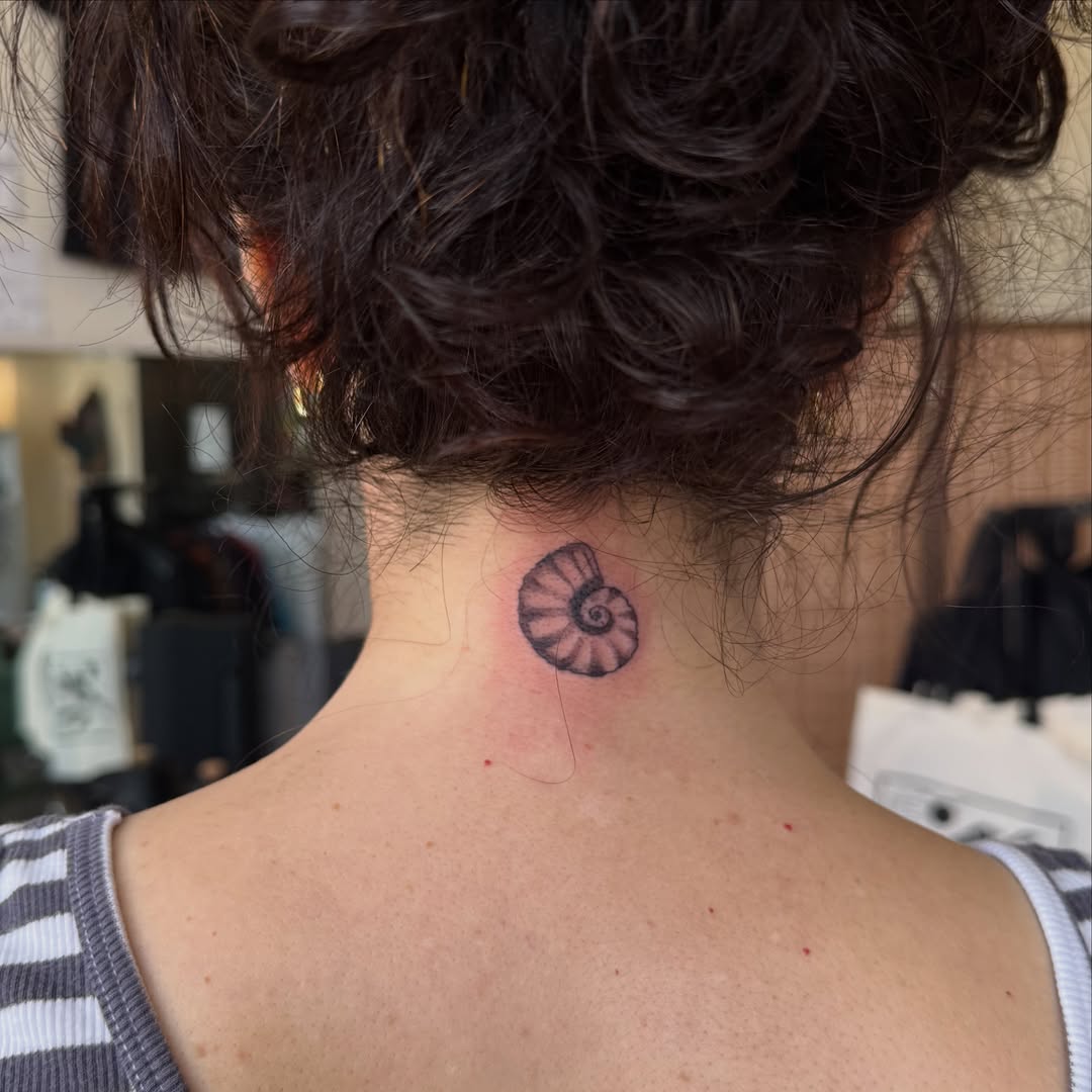 Nautilus shell black and grey tattoo on the neck by Leah - Tattoo Artist