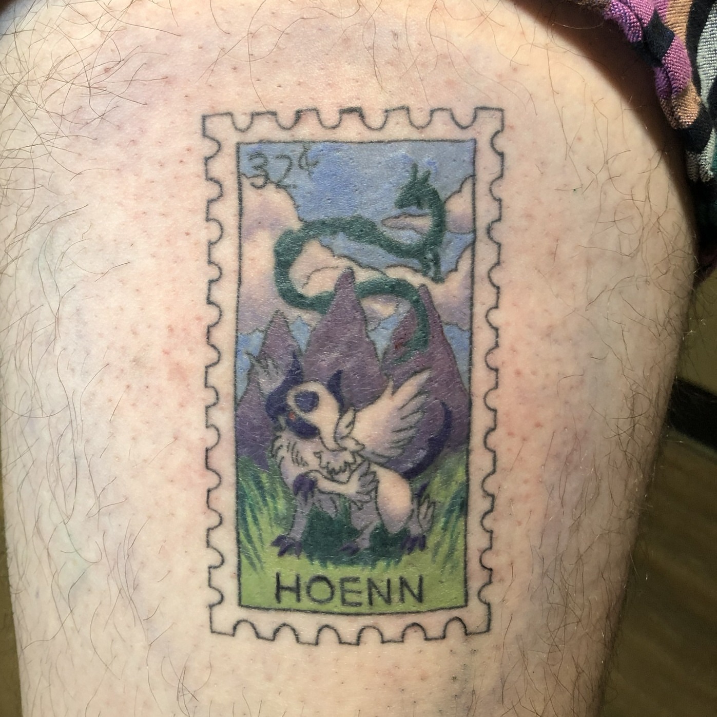Hoenn postage stamp illustrative tattoo on the thigh by Rowan Lee