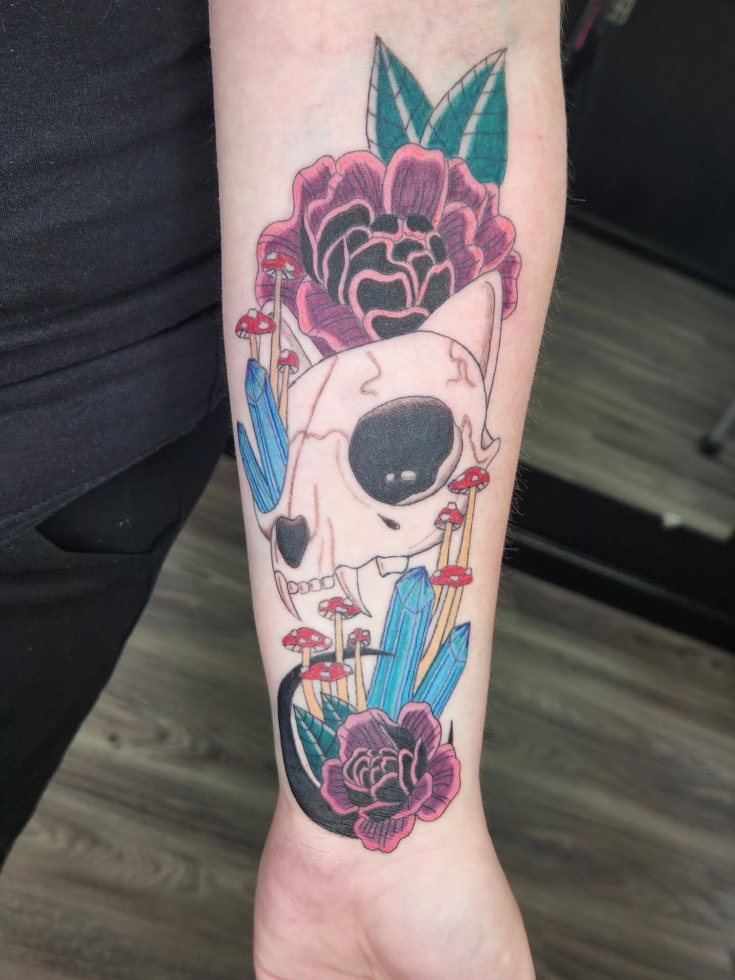 Skull and flowers neo-traditional tattoo on the forearm by Jessica Duggan