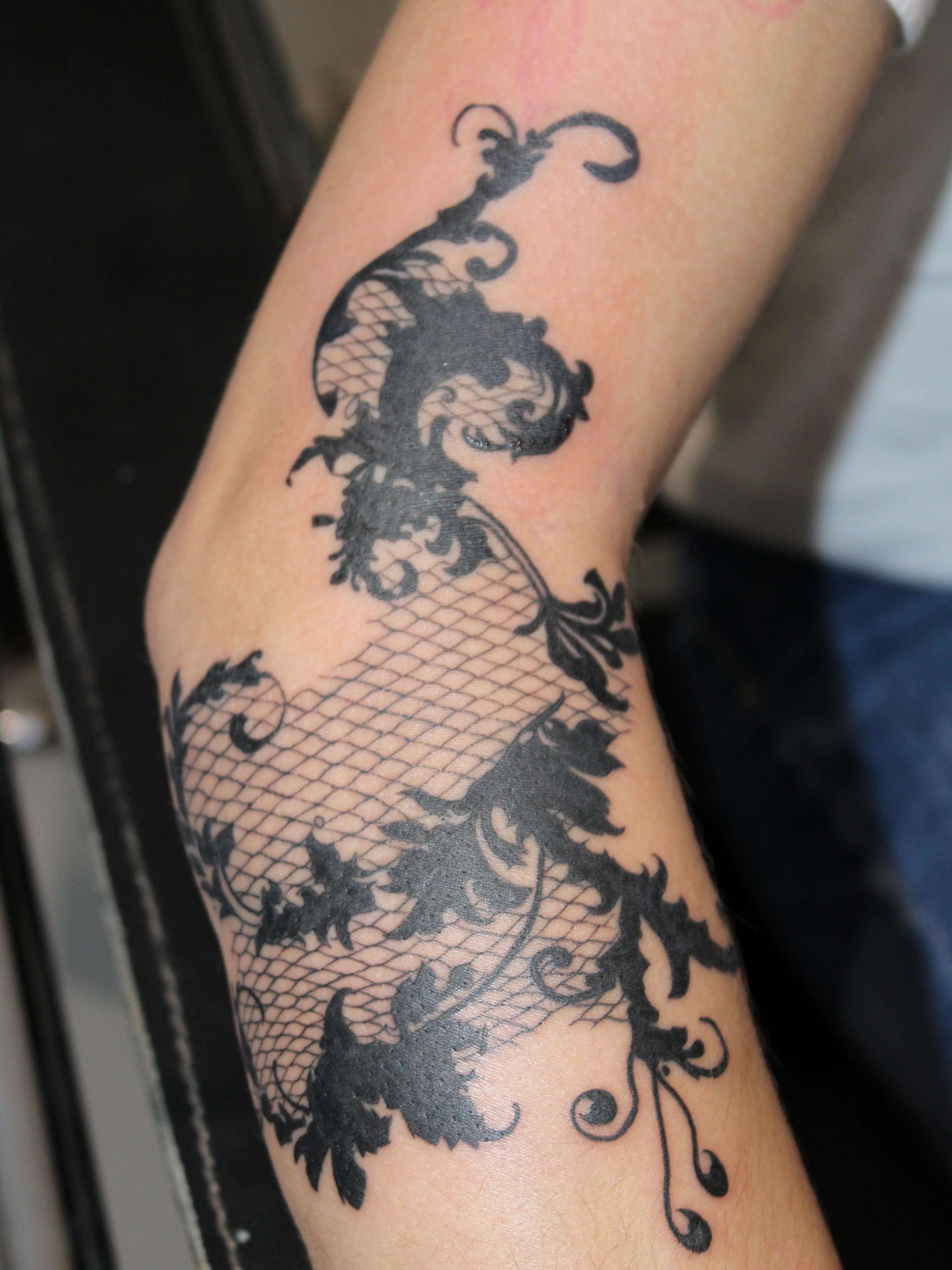 Lace and floral black and grey tattoo on the forearm by Julianna