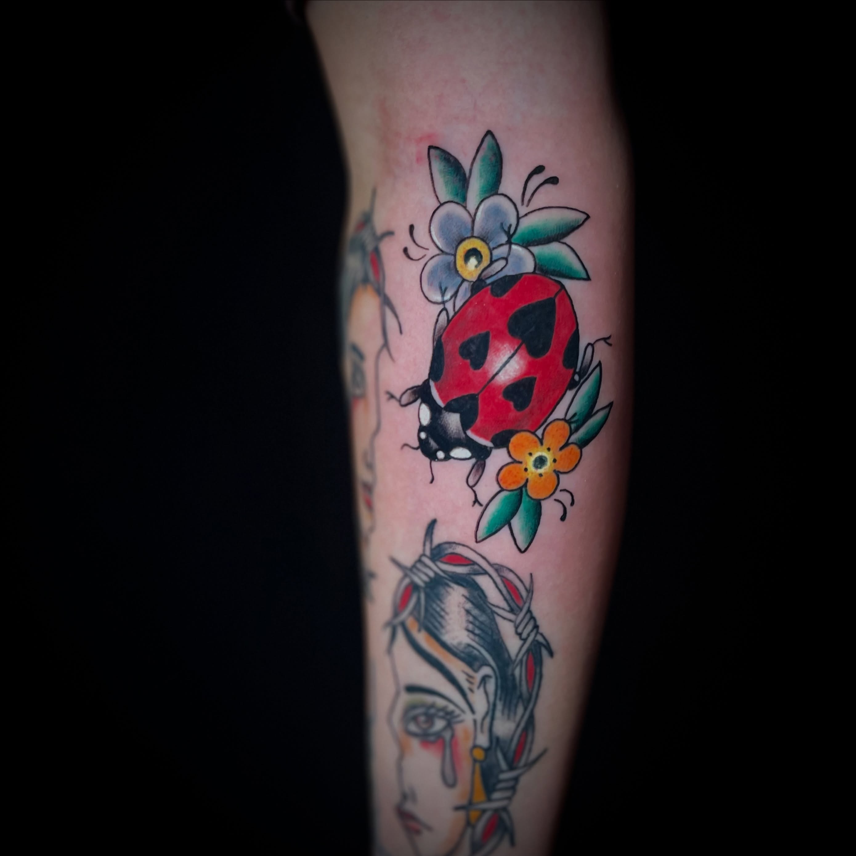 Ladybug and flowers American traditional tattoo on the forearm by MoogieTats