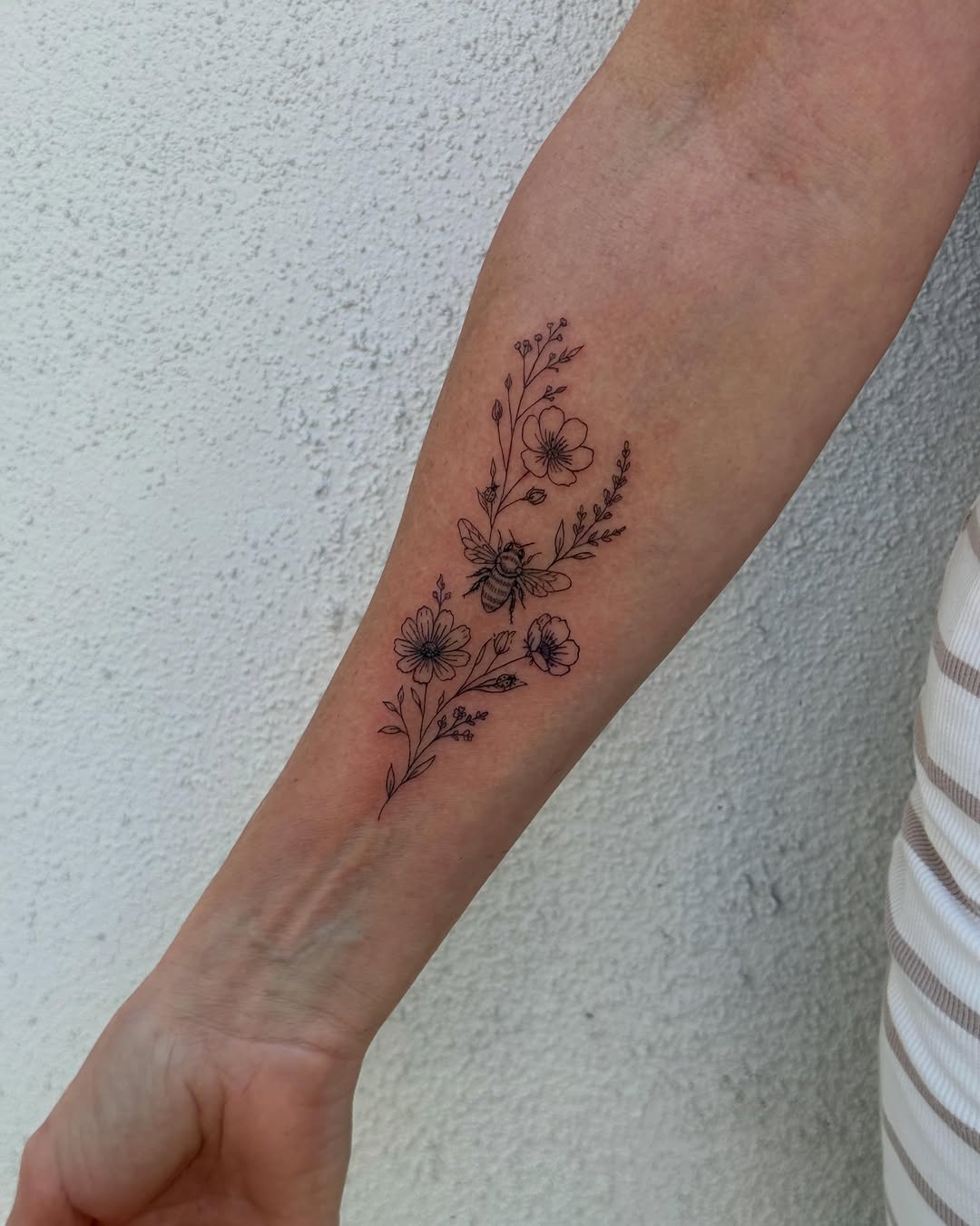 Bee and flowers fine line tattoo on the forearm by TATTOO & PIERCING ARTIST ₊˚⊹ ᰔ
