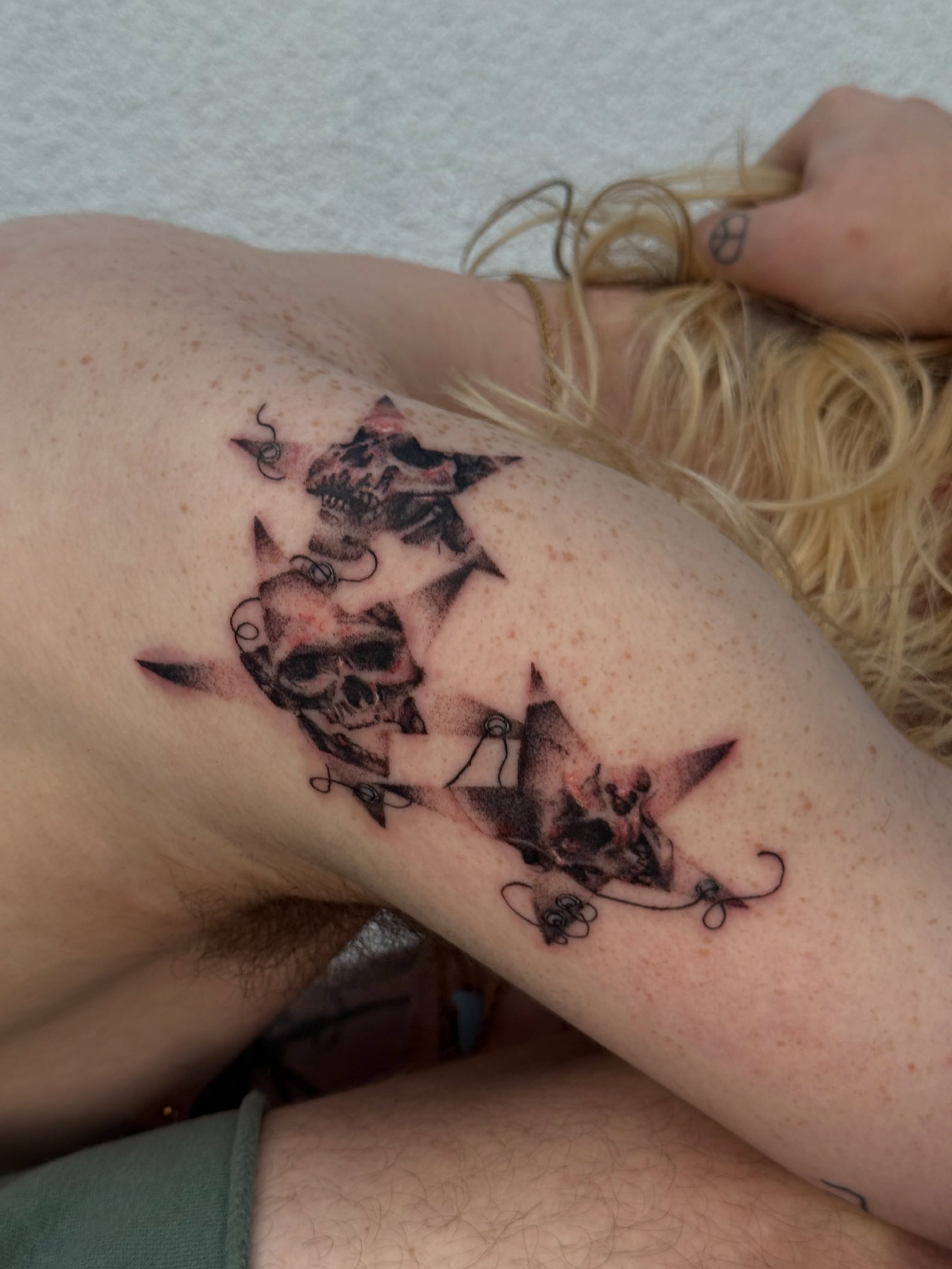 Skulls and stars realism tattoo on the upper arm by Ava Nilou