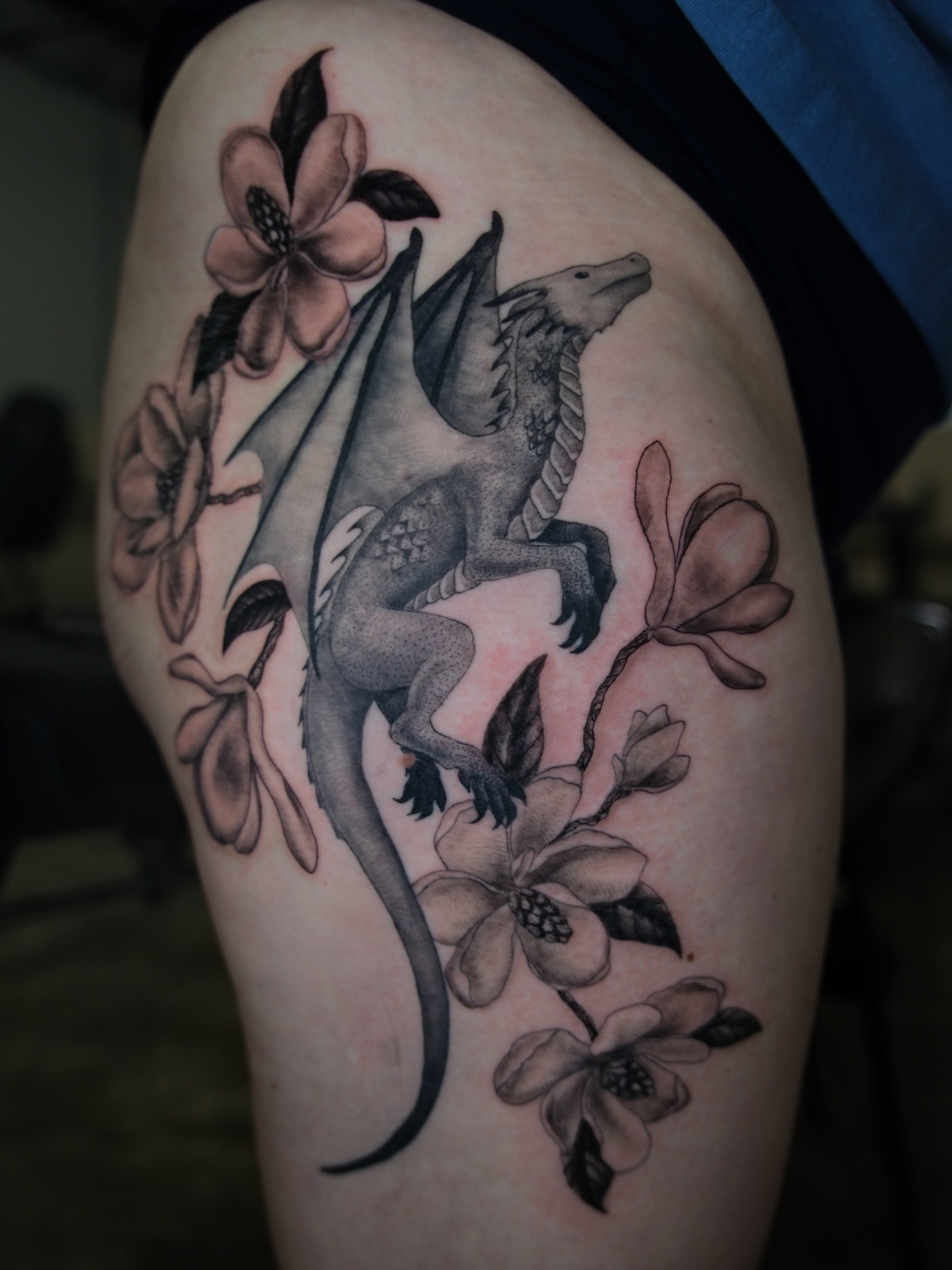 Dragon and flowers black and grey tattoo on the thigh by Kiana Hope