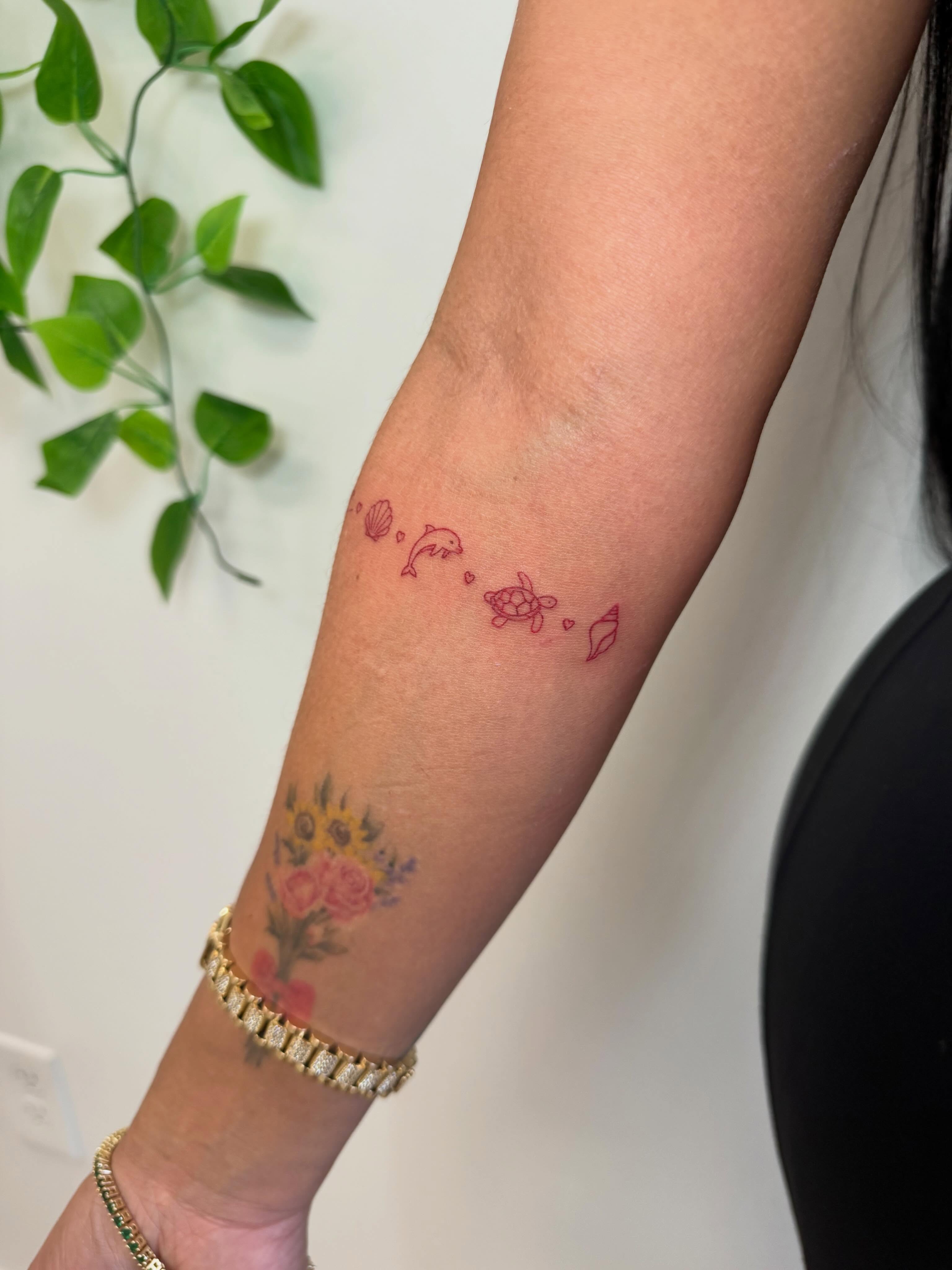 Seashells, dolphin, turtle, flower bouquet dotwork tattoo on the forearm by Angela Nery, South Jordan, Utah