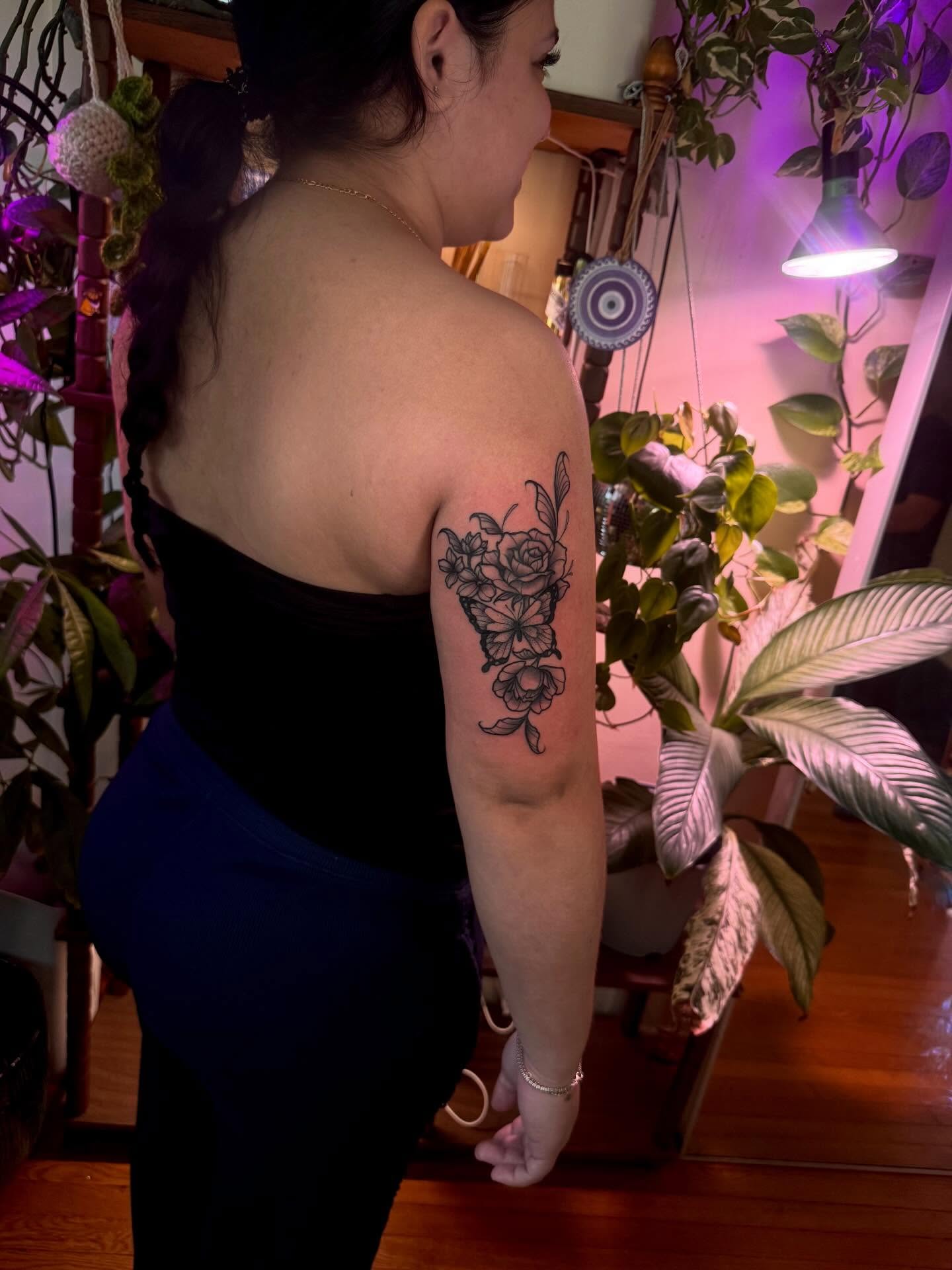 Floral bouquet black and grey tattoo on the upper arm by Angie Cotton