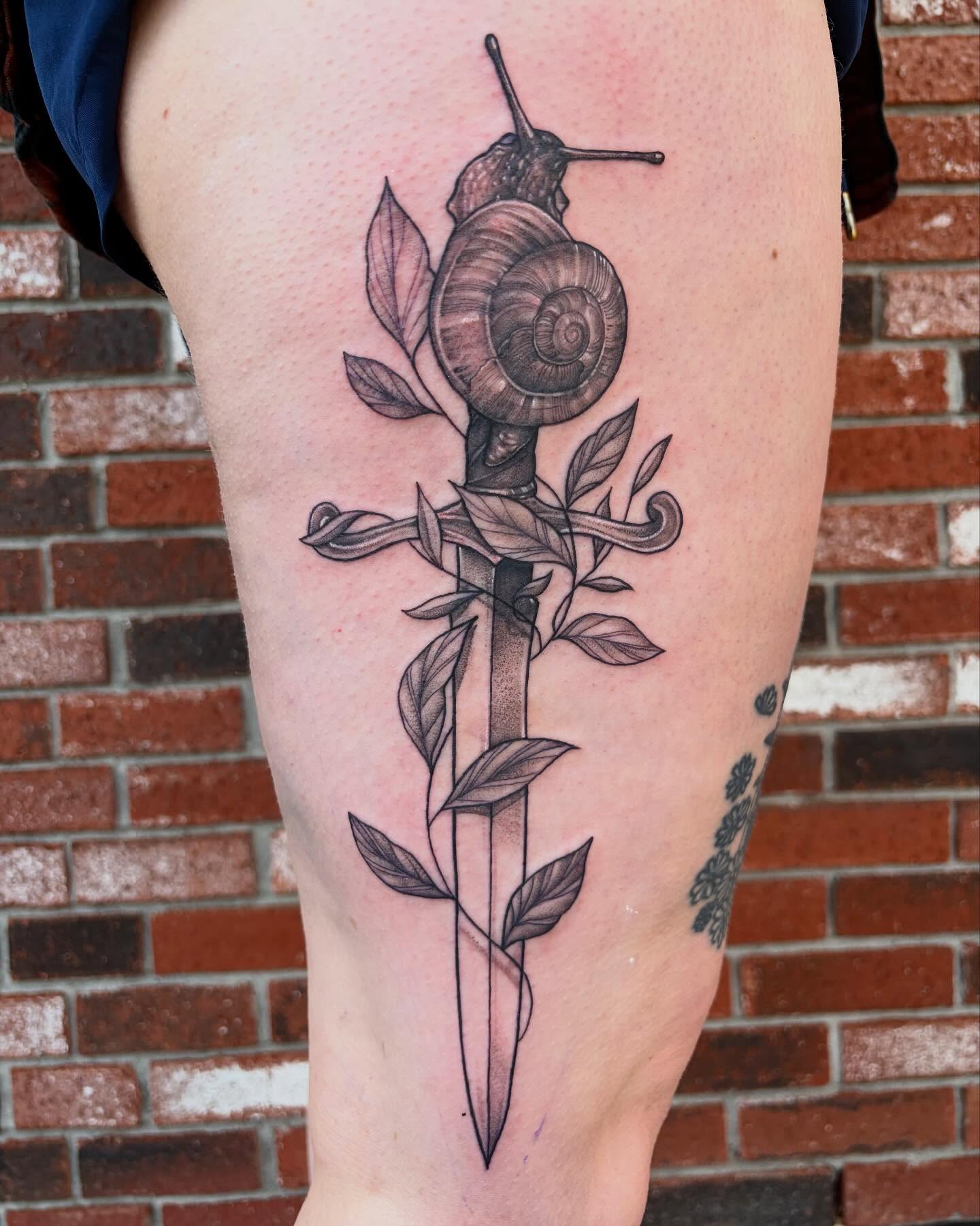 Snail and dagger realism tattoo on the thigh by Emily Falkowski