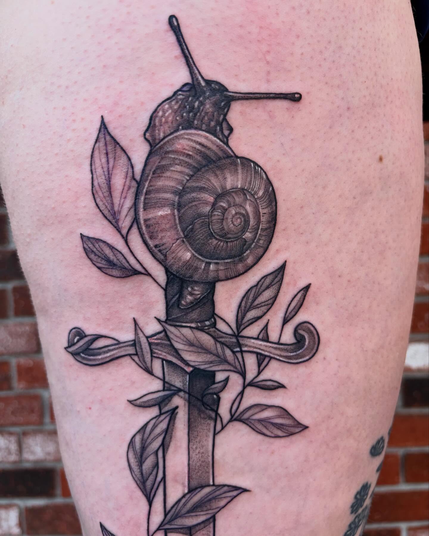 Snail and sword realism tattoo on the thigh by Emily Falkowski