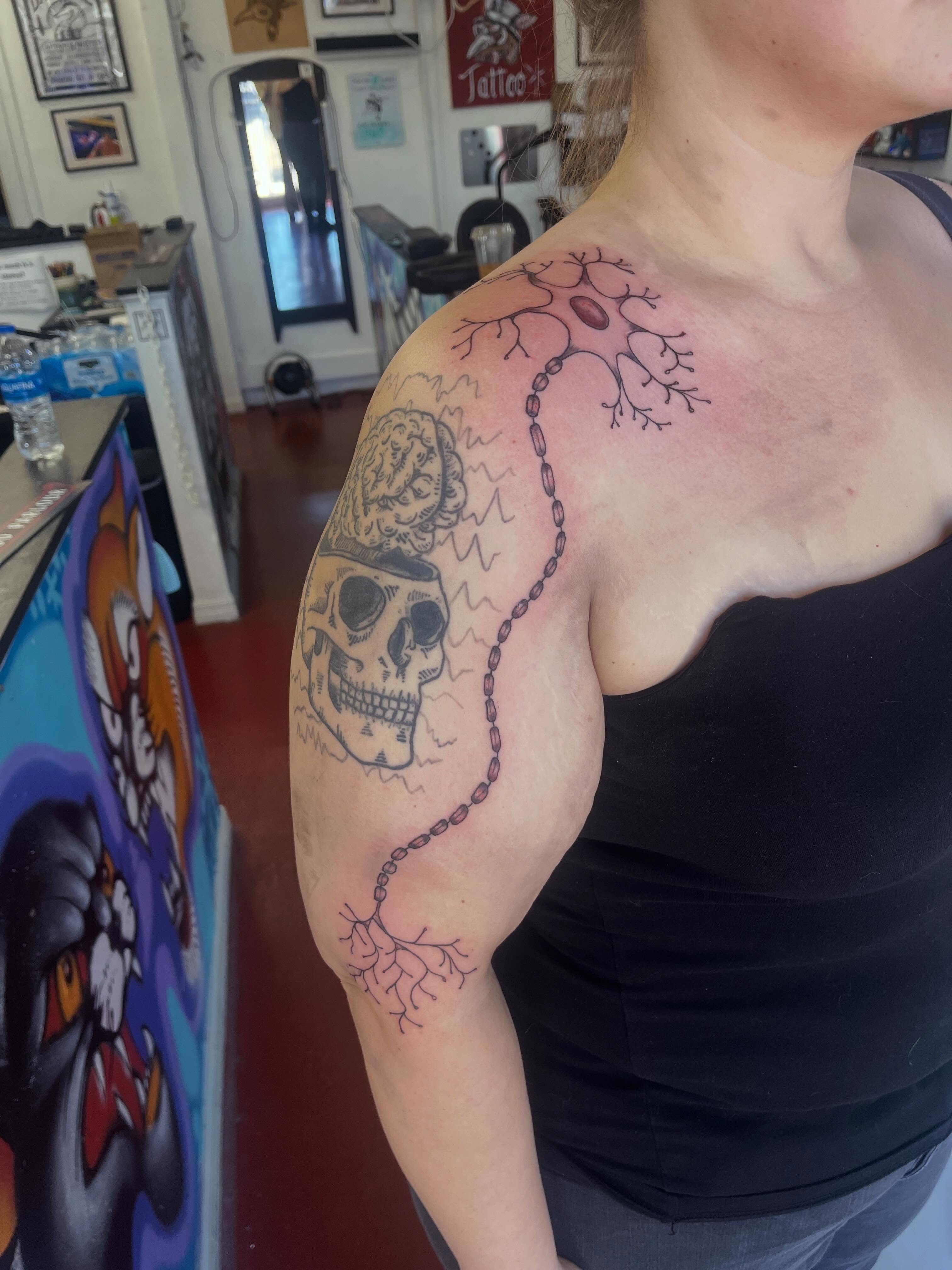 Skull and chain black and grey tattoo on the shoulder by Rafaela Lopez