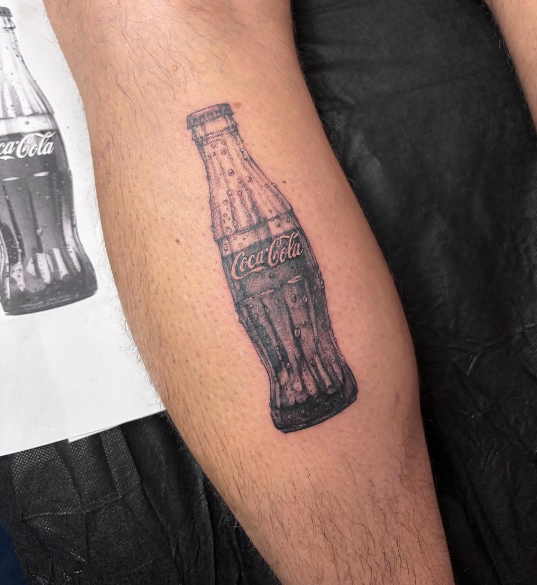 Coca-Cola bottle black and grey tattoo on the forearm by Mary Hannah Sosdian
