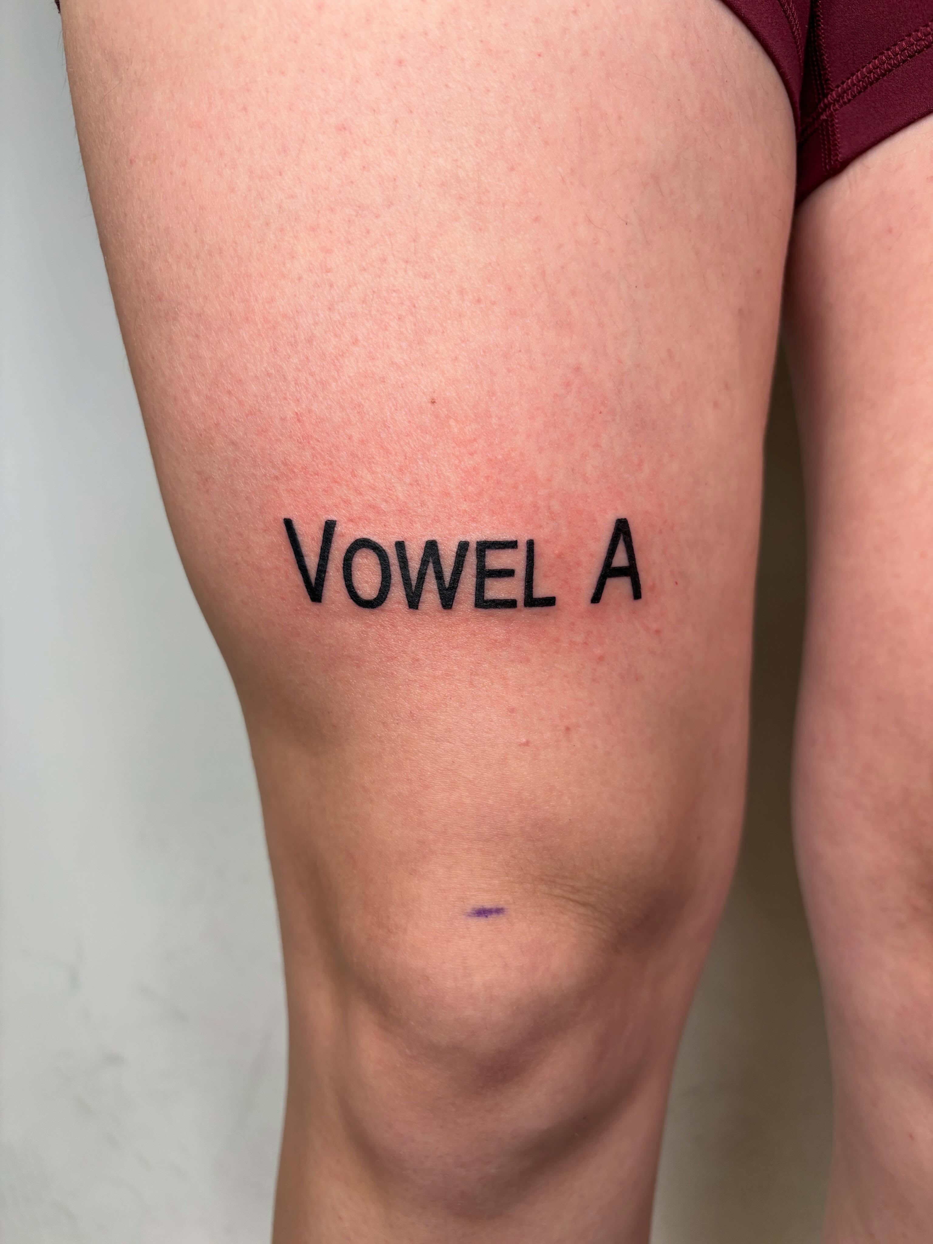 Vowel a lettering script tattoo on the thigh by Morgan