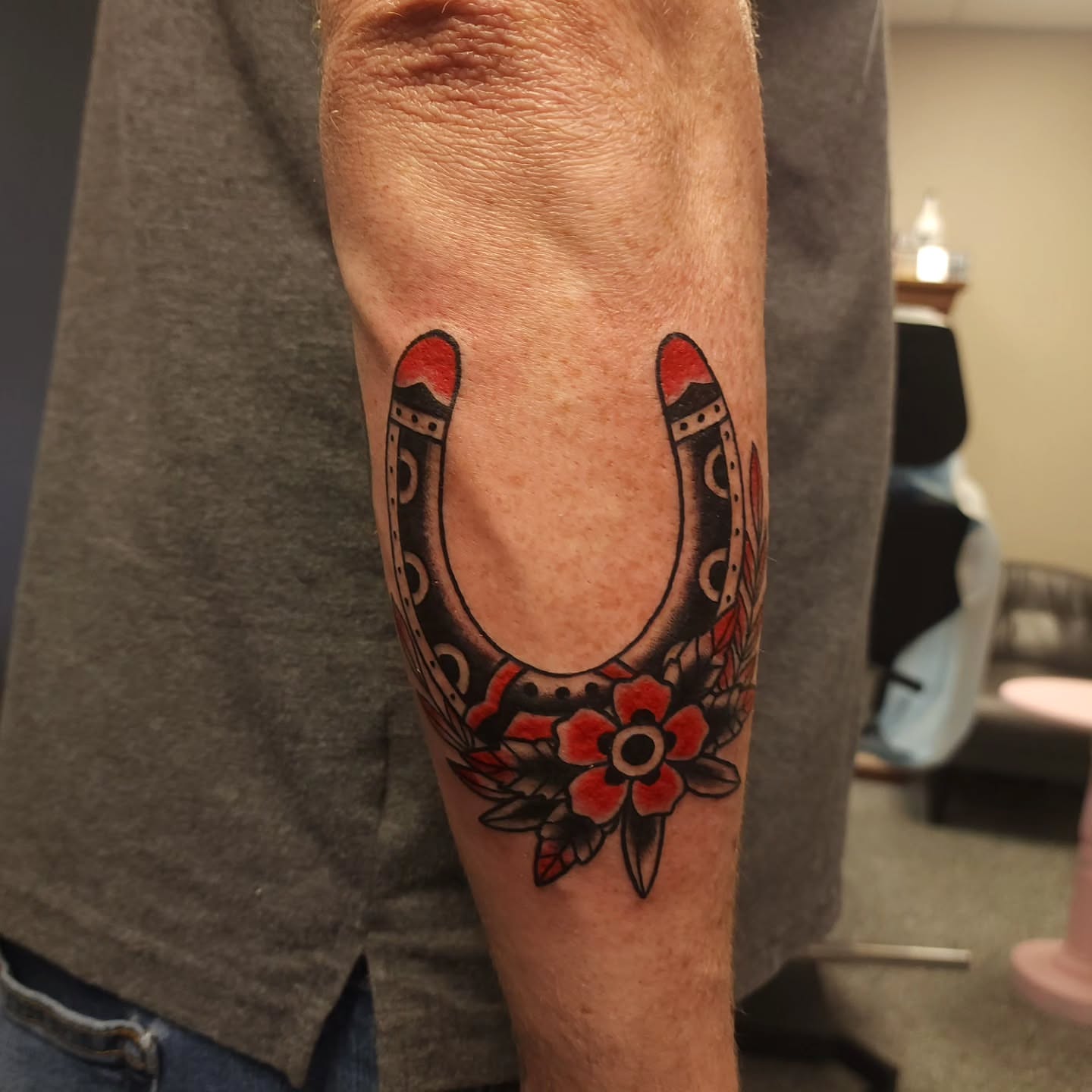 Horseshoe with floral wreath American traditional tattoo on the forearm by xavia