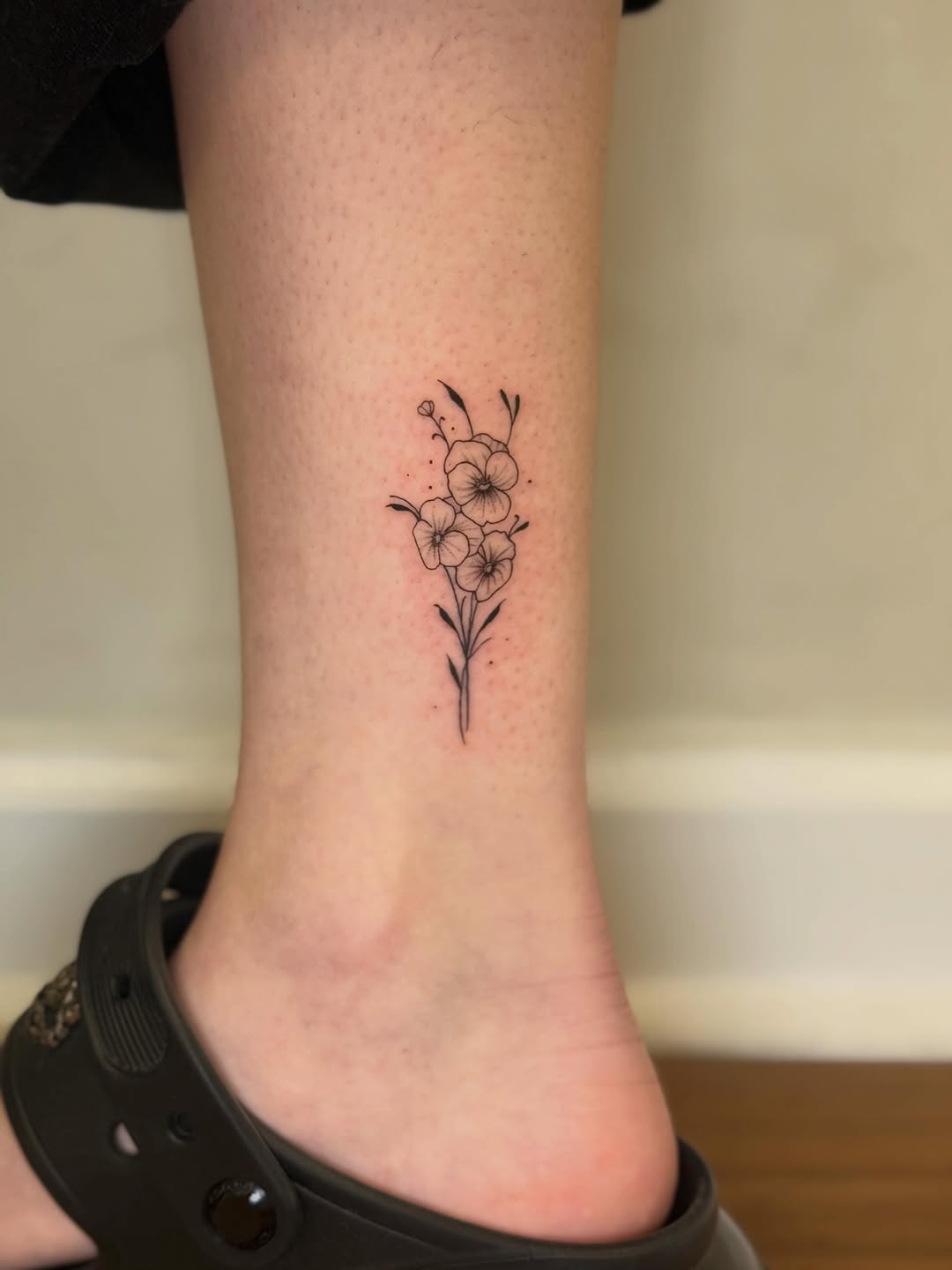 Small floral bouquet fine line tattoo on the foot by Danny Garcia