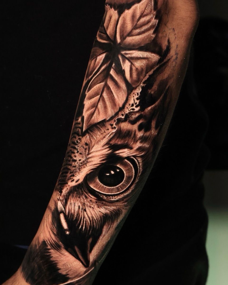 Owl eye and leaves surrealism tattoo on the forearm by German Patiño.