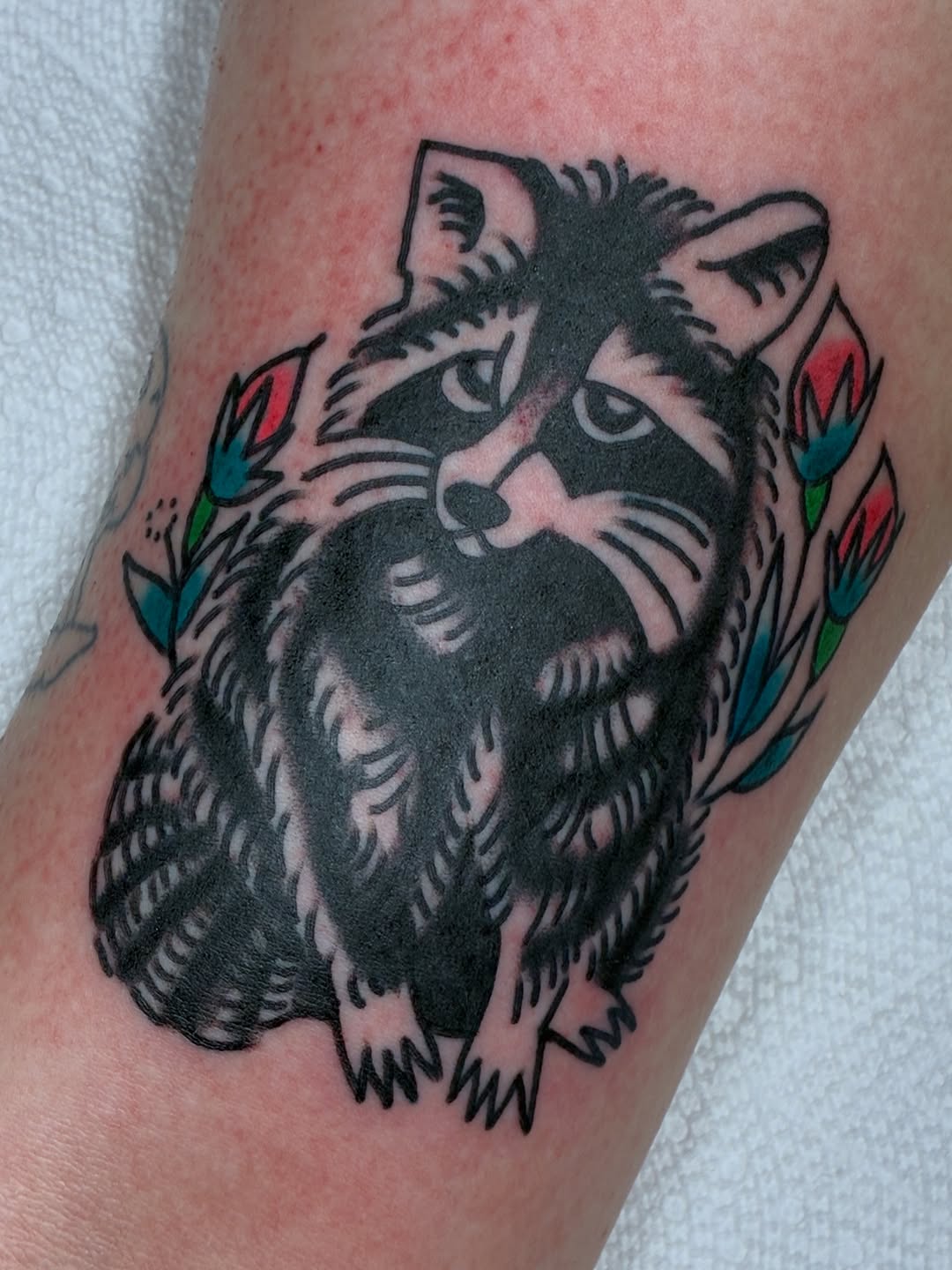 Raccoon with flowers realism tattoo on the forearm by Sav Robinson