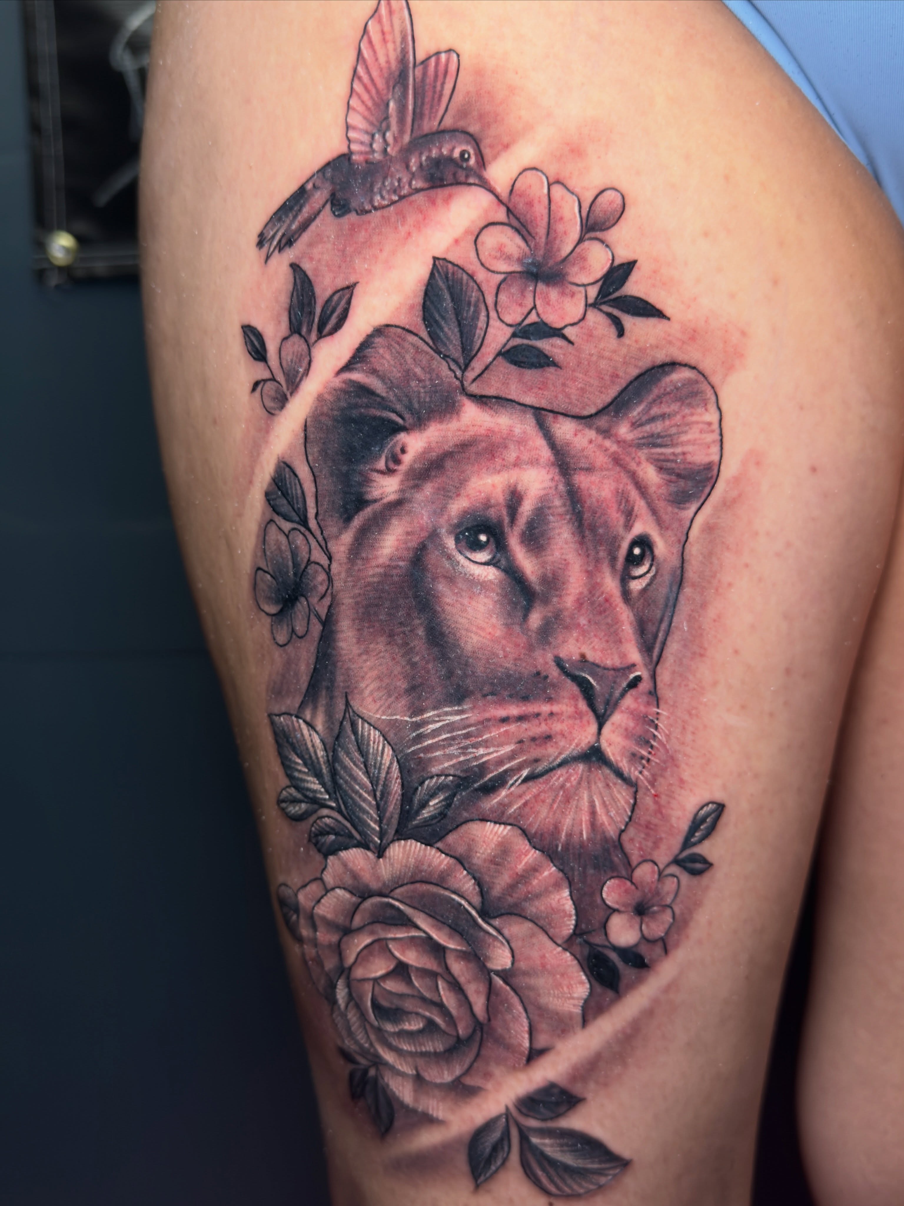 Lion with flowers realism tattoo on the thigh by Dallas tattoo artist, Dallas, Texas